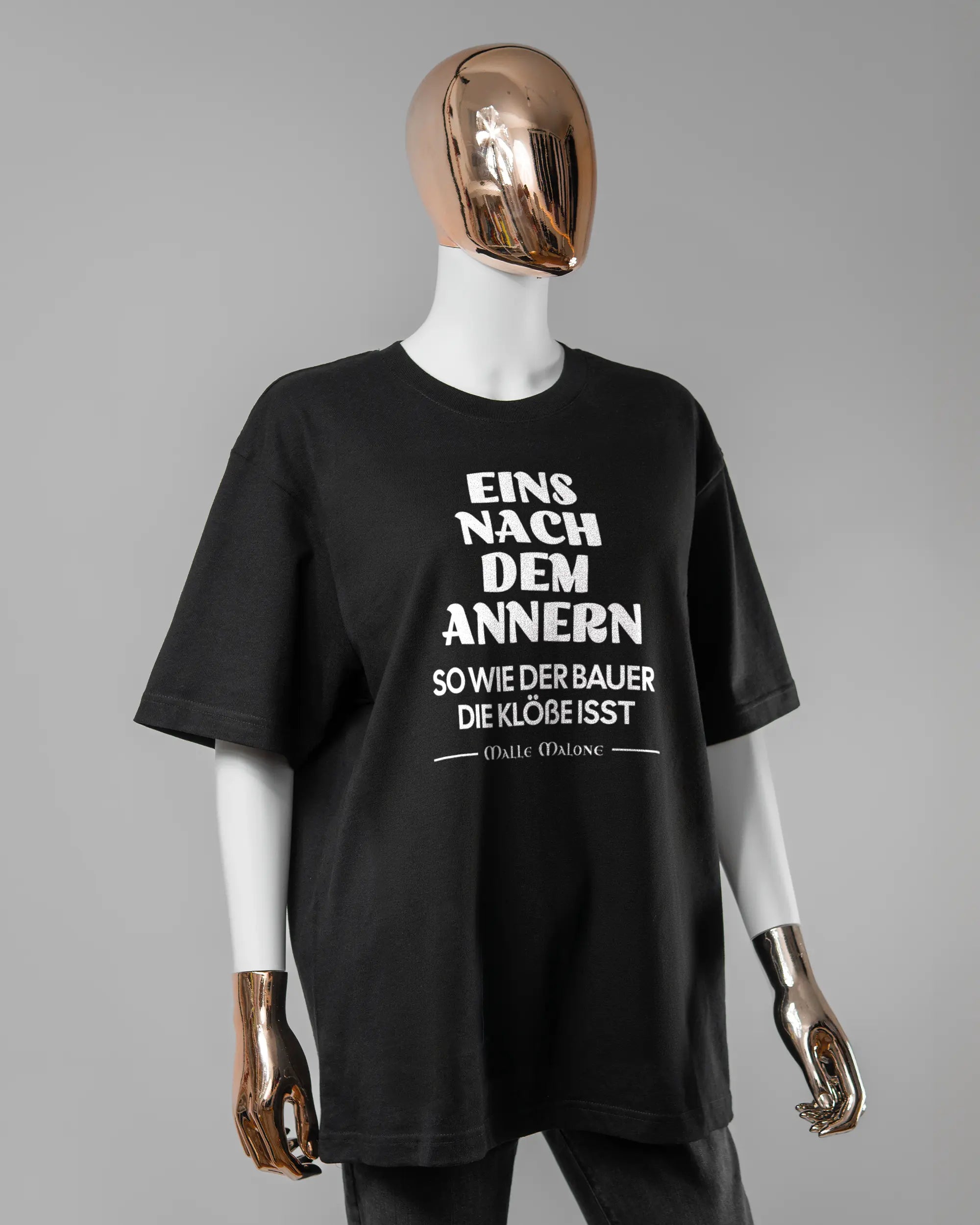 Vorderseite des Basic Unisex T-Shirt Oversized von Maondo mit dem Design Eins nach dem Annern in der Farbe Black und in der Größe S getragen von einer femininen Puppe