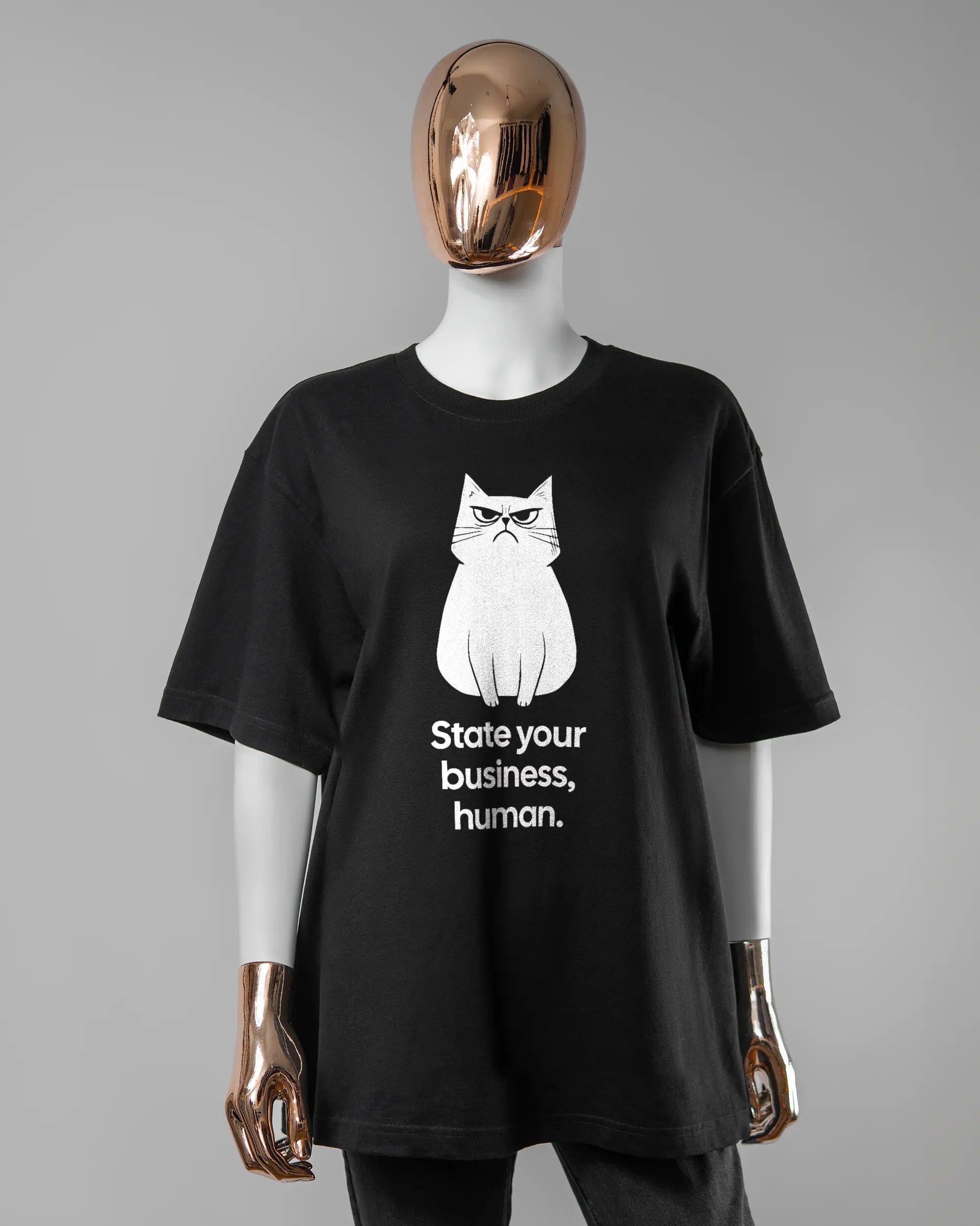 Vorderseite des Basic Unisex T-Shirt Oversized von Maondo mit dem Design Grumpy Purr in der Farbe Black und in der Größe S getragen von einer femininen Puppe