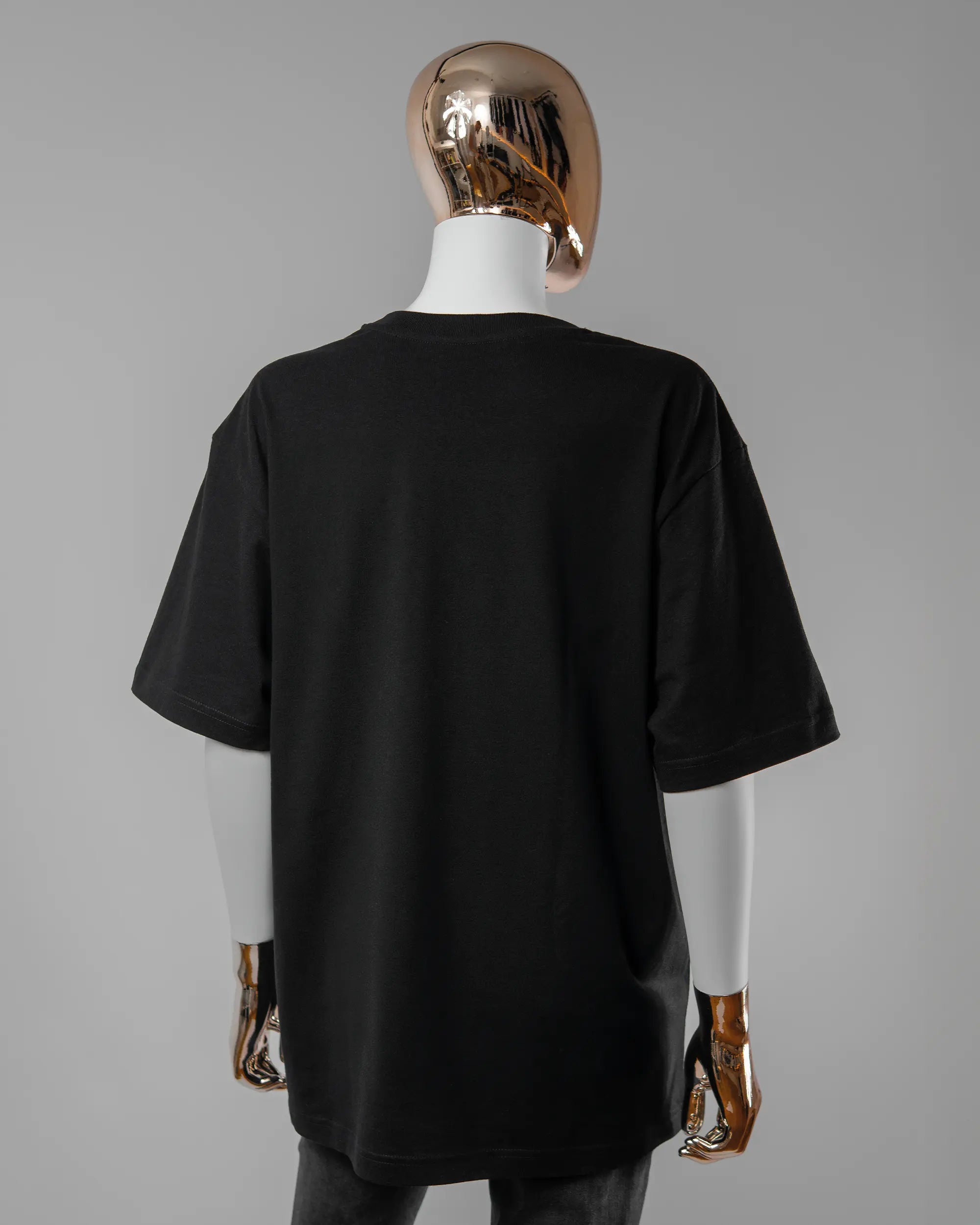 Rückseite des Basic Unisex T-Shirt Oversized von Maondo ohne Motiv in der Farbe Black und in der Größe S getragen von einer femininen Puppe