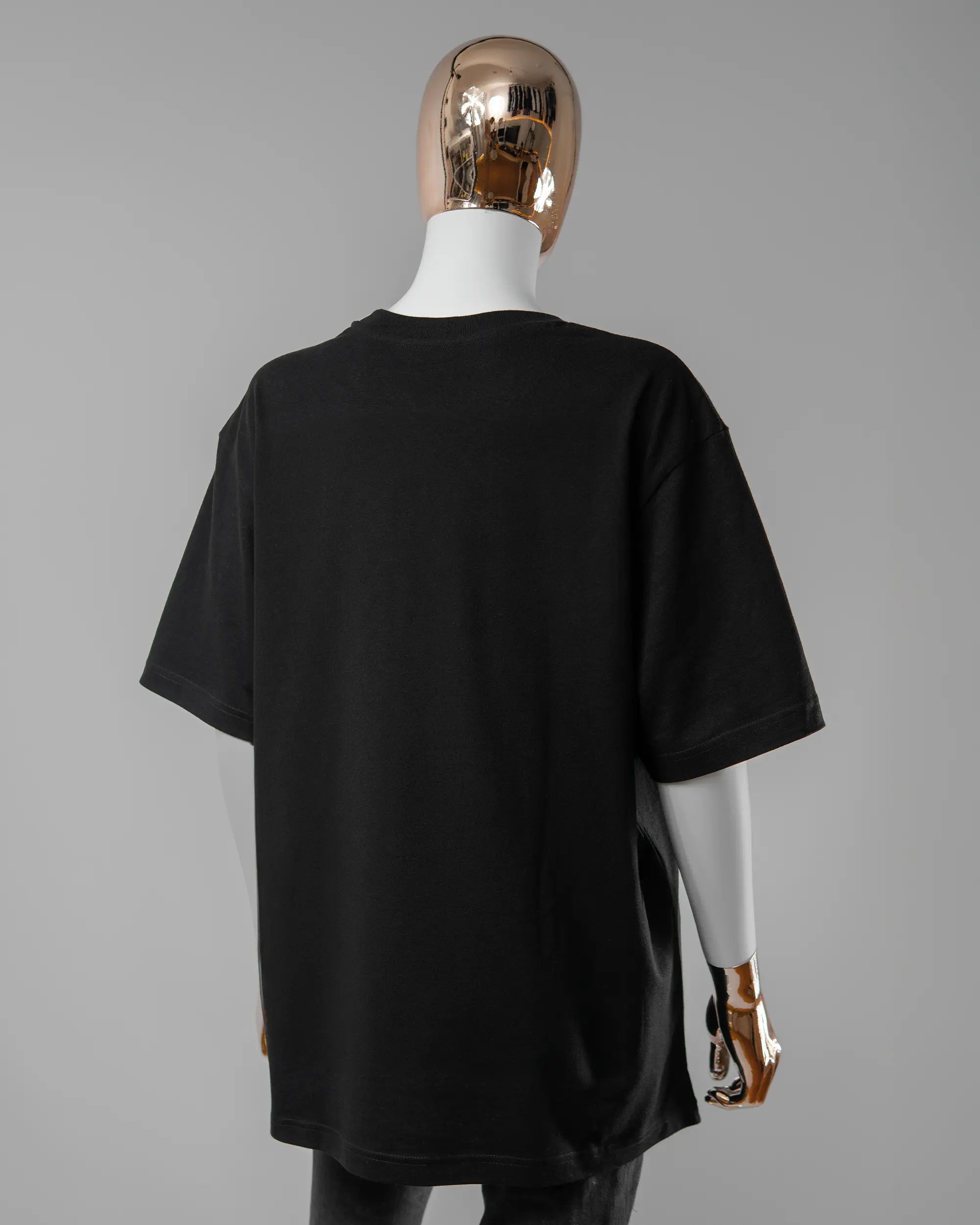 Rückseite des Basic Unisex T-Shirt Oversized von Maondo ohne Motiv in der Farbe Black und in der Größe S getragen von einer femininen Puppe