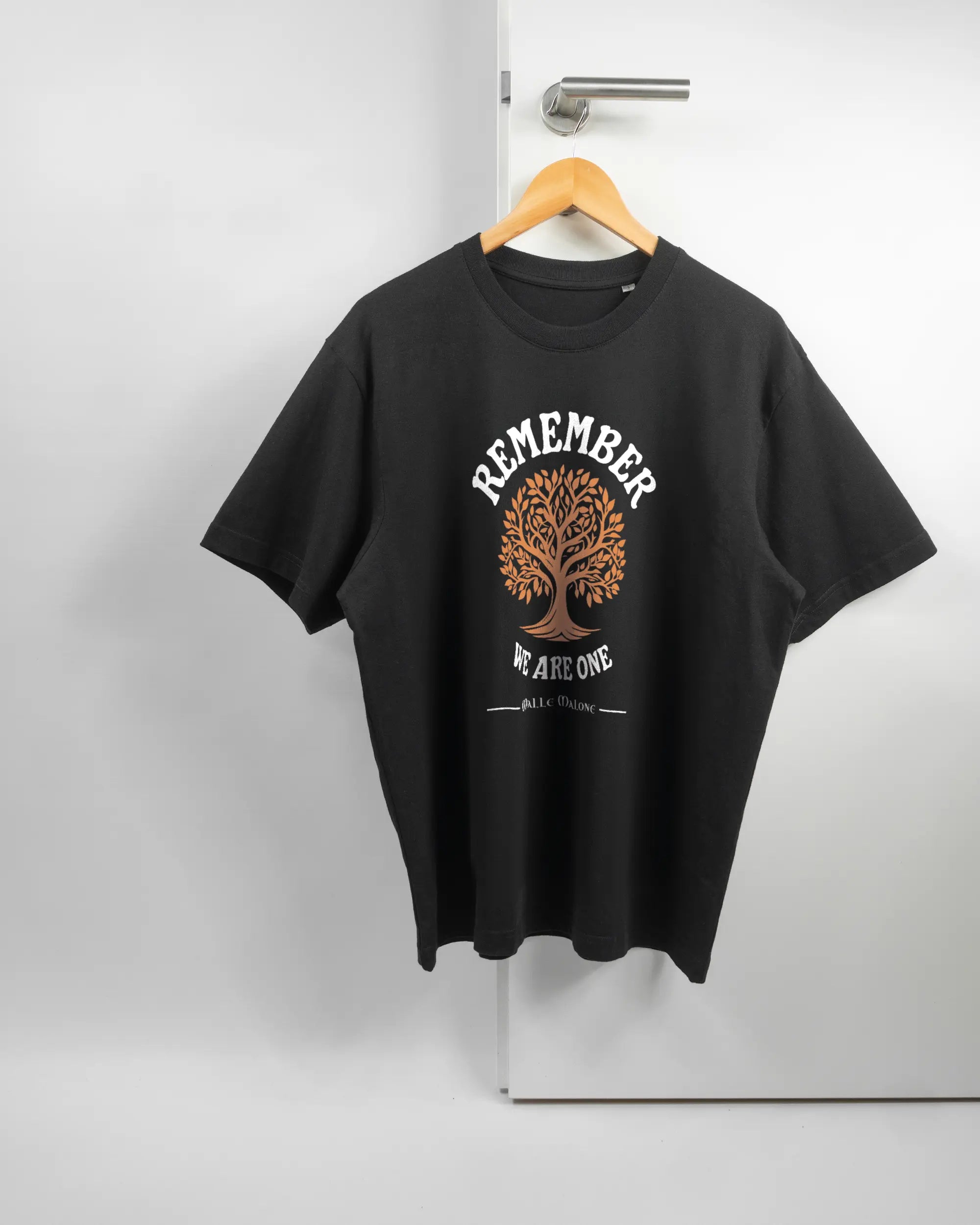 Vorderseite des Basic Unisex T-Shirt Oversized von Maondo mit dem Design We are one in der Farbe Black und in der Größe S auf einem Bügel an der Türklinke aufgehängt