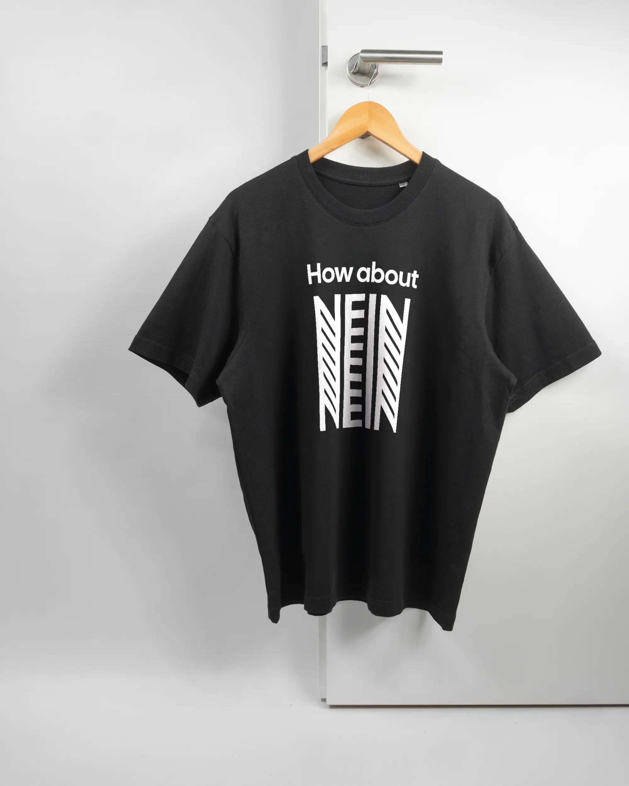 Vorderseite des Basic Unisex T-Shirt Oversized von Maondo mit dem Design How about nein in der Farbe Black und in der Größe S auf einem Bügel an der Türklinke aufgehängt