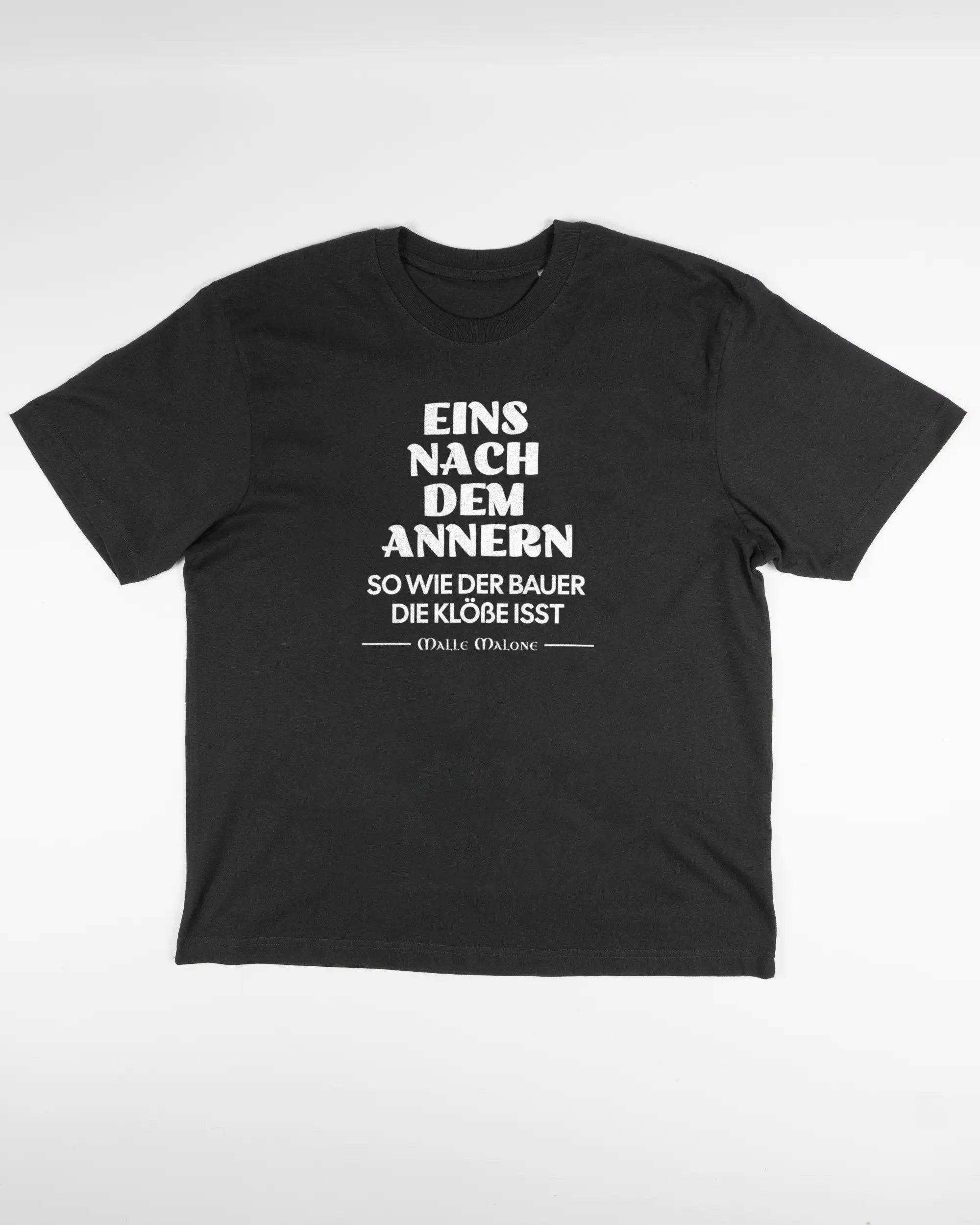 Vorderseite des Basic Unisex T-Shirt Oversized von Maondo mit dem Design Eins nach dem Annern in der Farbe Black und in der Größe S flach auf den Boden gelegt