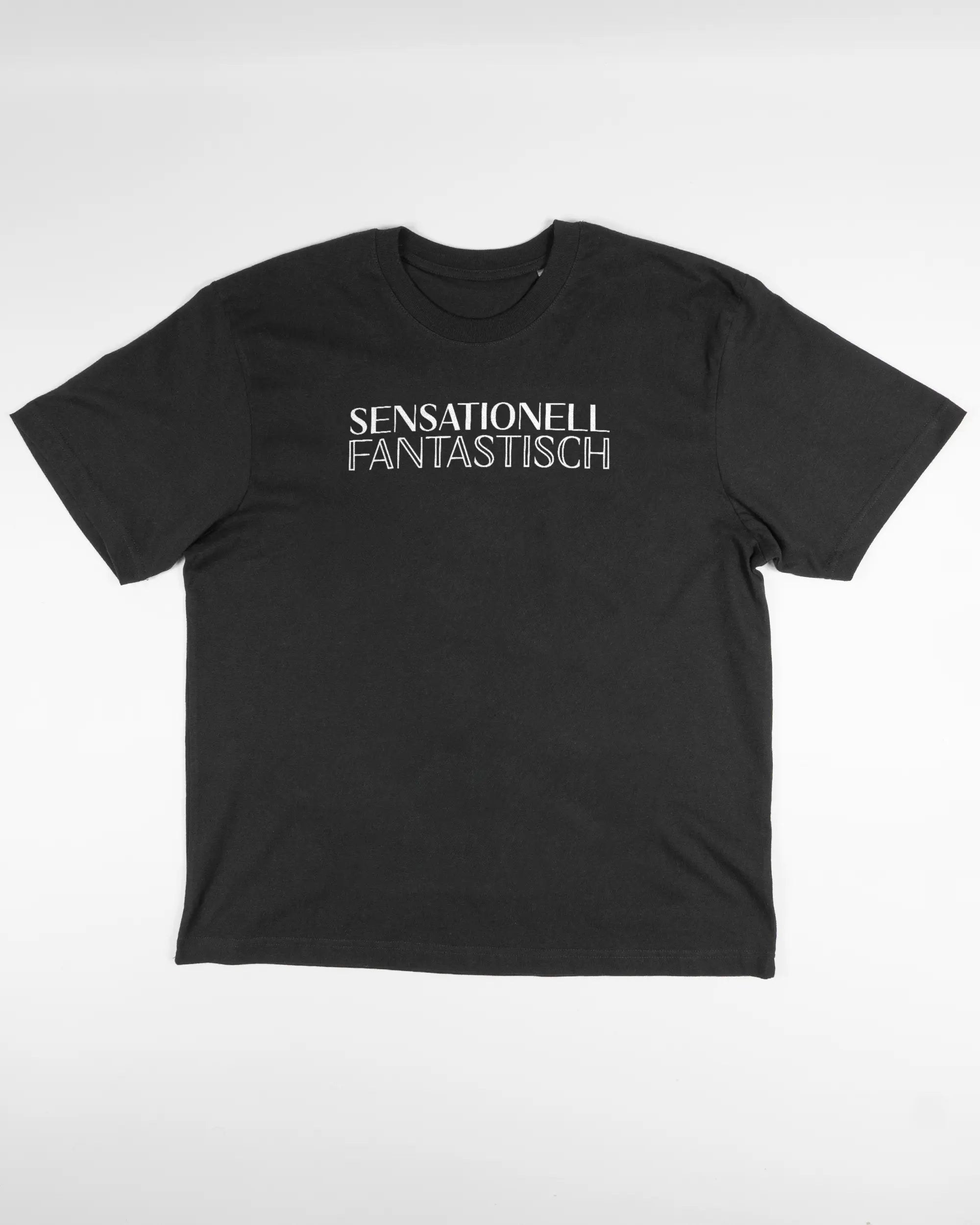 Vorderseite des Basic Unisex T-Shirt Oversized von Maondo mit dem Design Sensationell in der Farbe Black und in der Größe S flach auf den Boden gelegt