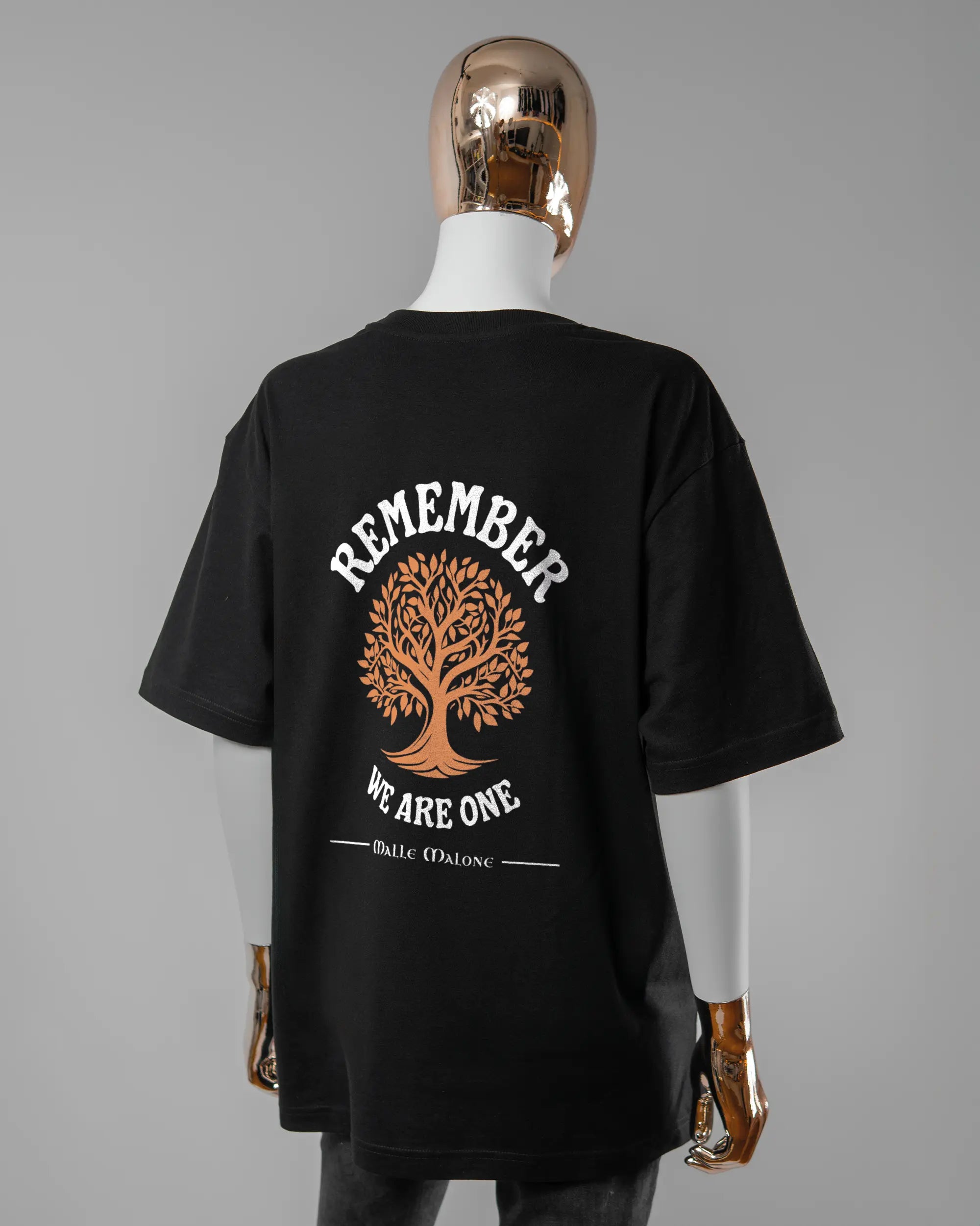 Rückseite des Basic Unisex T-Shirt Oversized von Maondo mit dem Design We are one in der Farbe Black und in der Größe S getragen von einer femininen Puppe