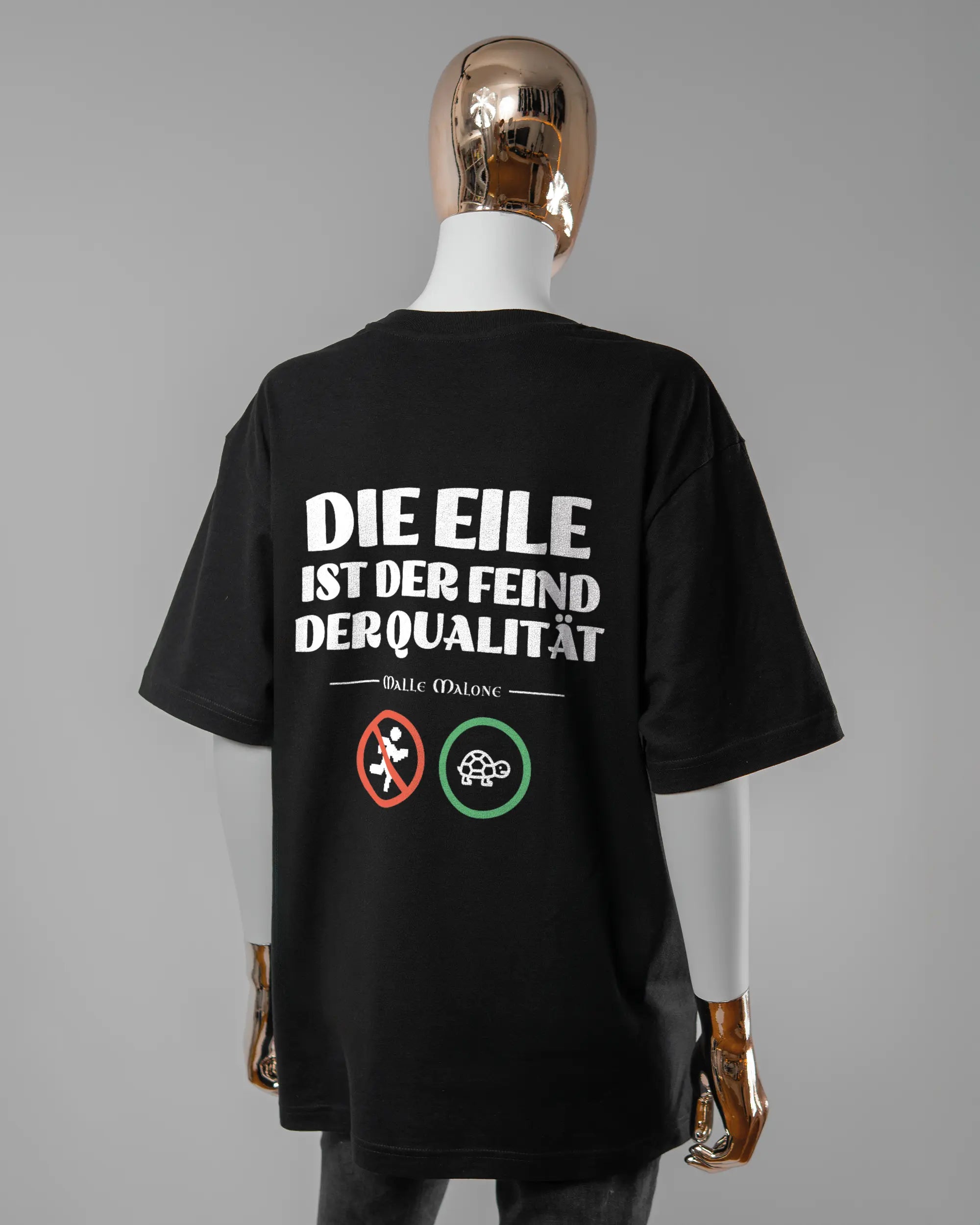 Rückseite des Basic Unisex T-Shirt Oversized von Maondo mit dem Design Keine Eile in der Farbe Black und in der Größe S getragen von einer femininen Puppe
