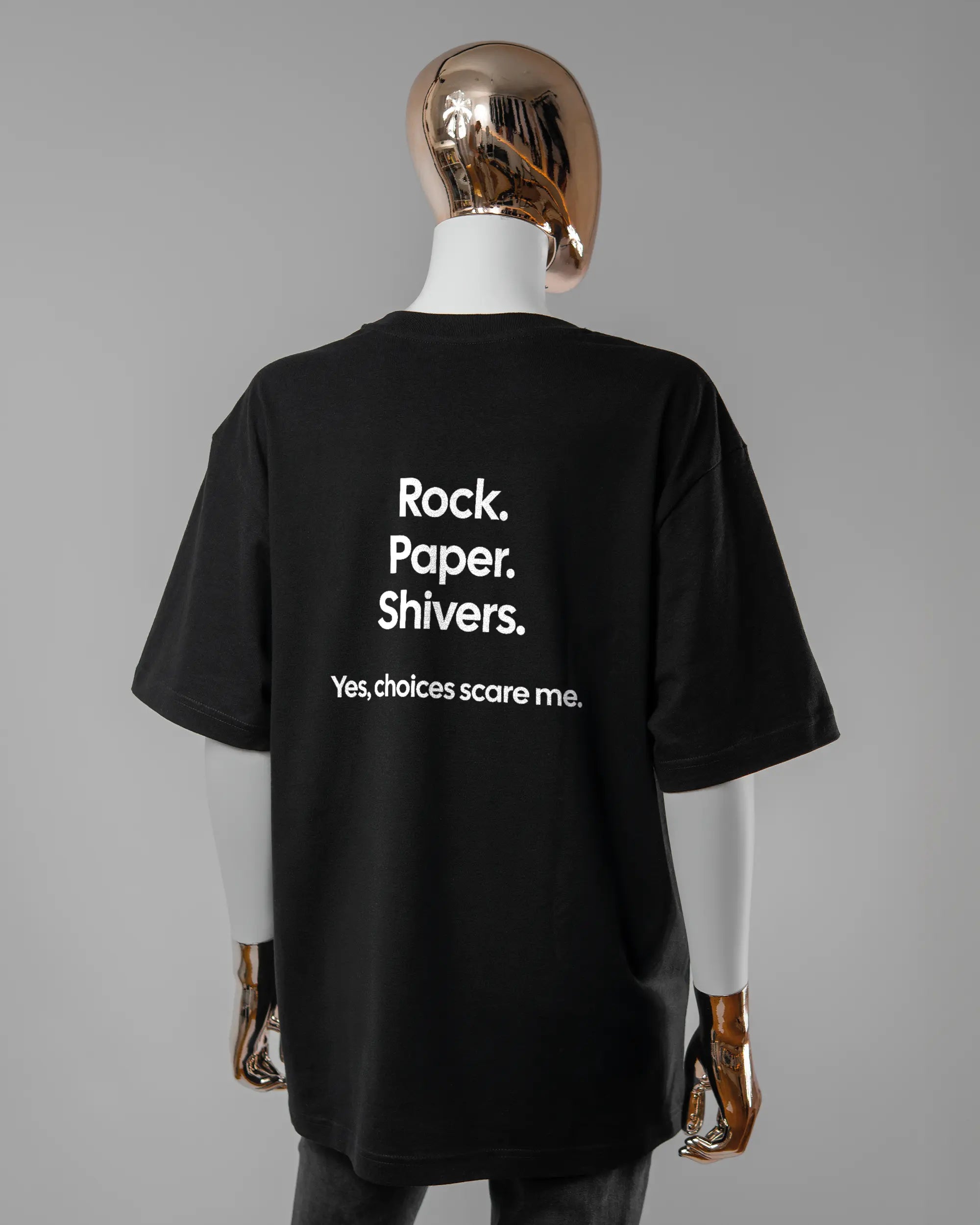 Rückseite des Basic Unisex T-Shirt Oversized von Maondo mit dem Design Rock Paper Shivers in der Farbe Black und in der Größe S getragen von einer femininen Puppe
