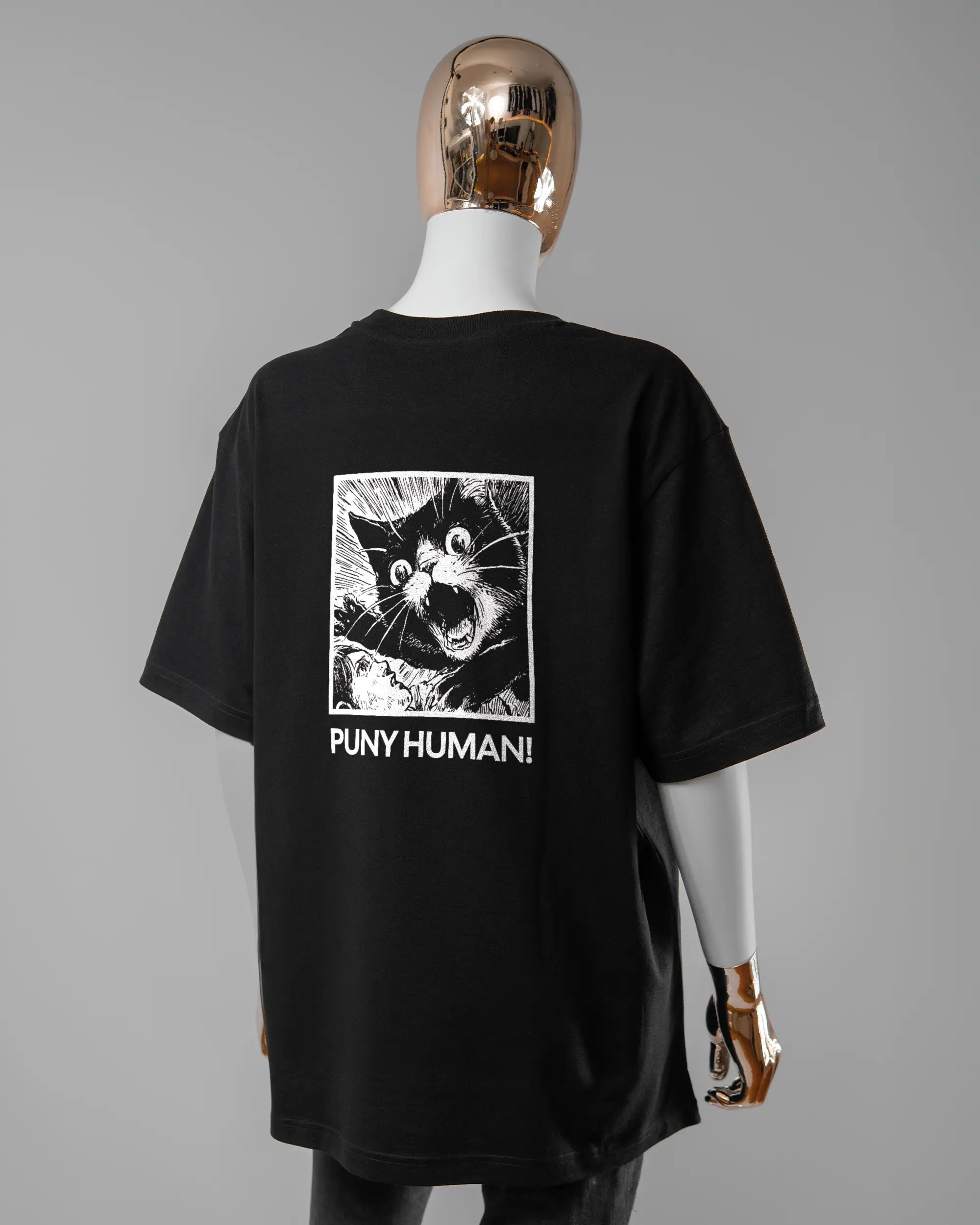 Rückseite des Basic Unisex T-Shirt Oversized von Maondo mit dem Design Puny Human in der Farbe Black und in der Größe S getragen von einer femininen Puppe