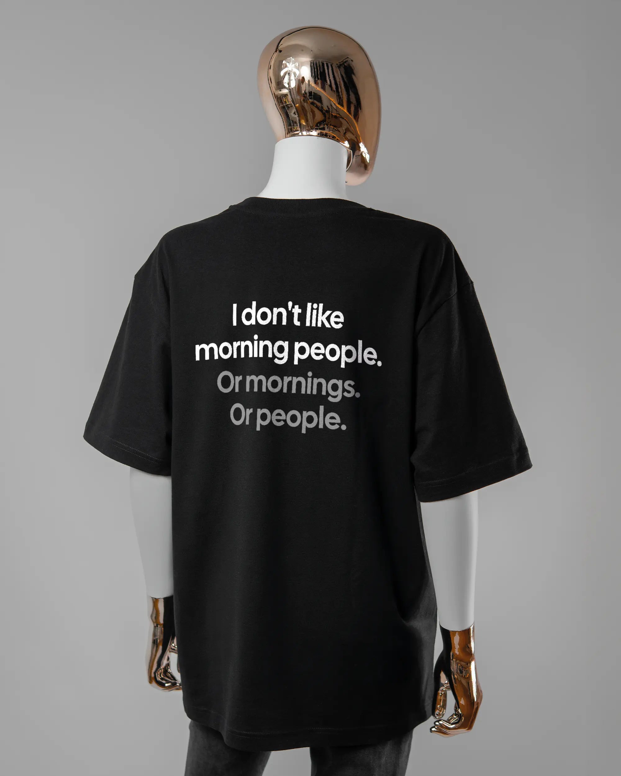 Rückseite des Basic Unisex T-Shirt Oversized von Maondo mit dem Design Morning Person in der Farbe Black und in der Größe S getragen von einer femininen Puppe