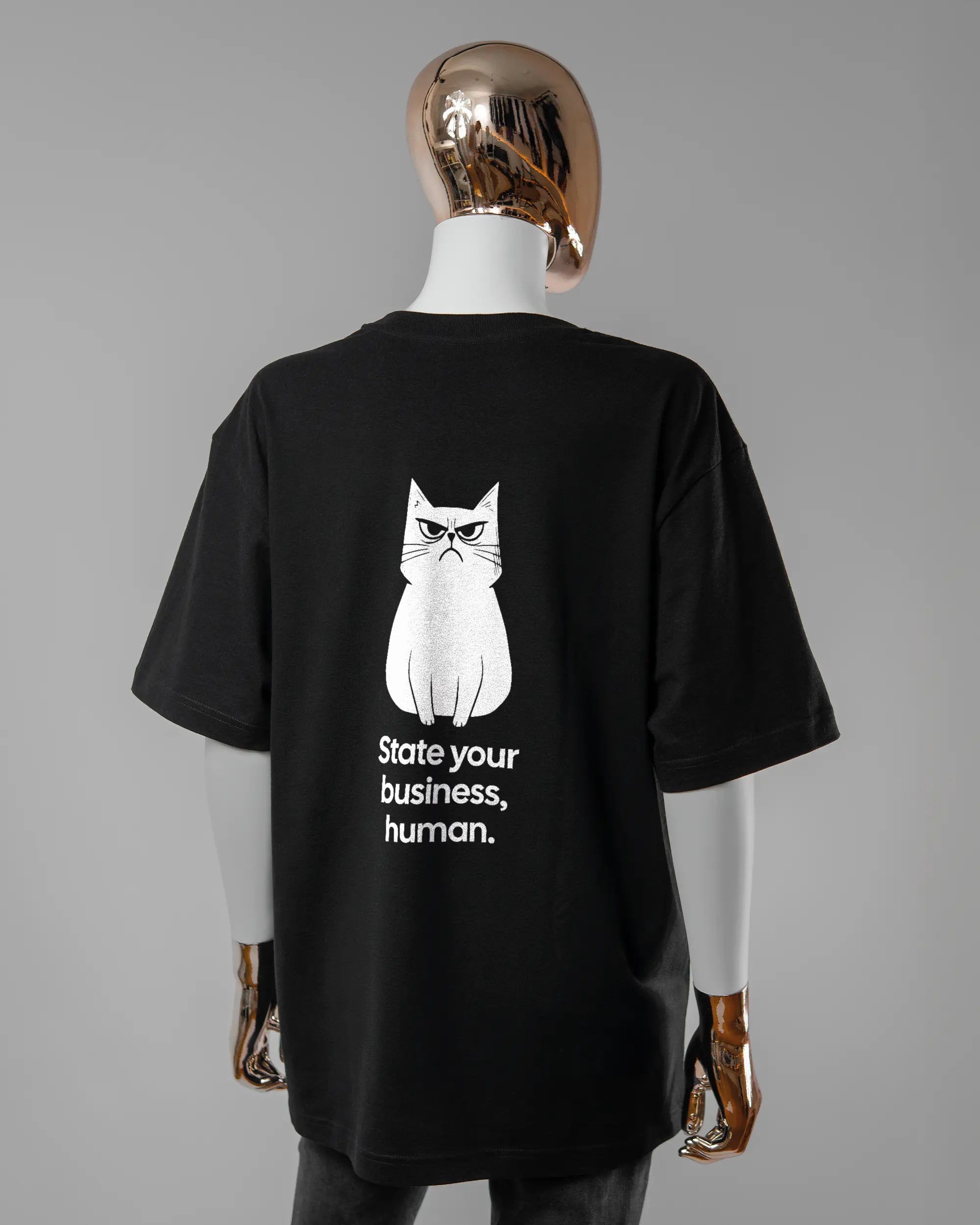 Rückseite des Basic Unisex T-Shirt Oversized von Maondo mit dem Design Grumpy Purr in der Farbe Black und in der Größe S getragen von einer femininen Puppe