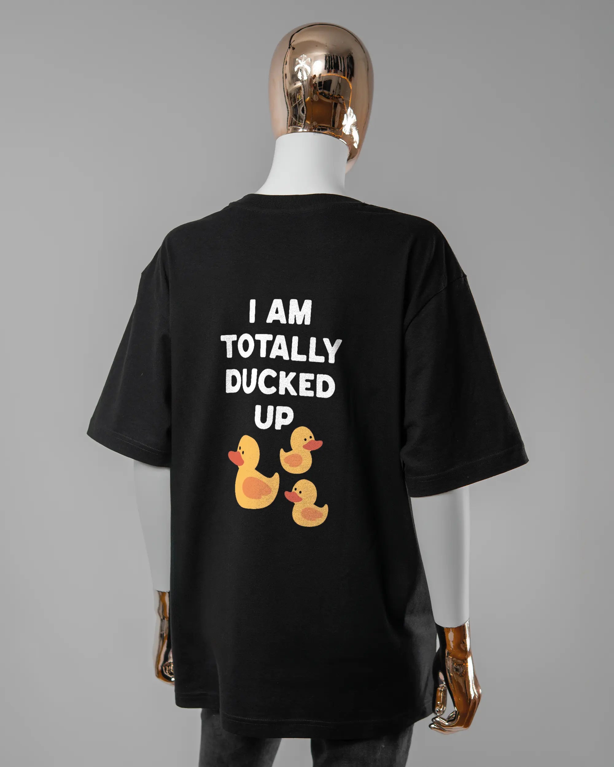 Rückseite des Basic Unisex T-Shirt Oversized von Maondo mit dem Design Ducked Up in der Farbe Black und in der Größe S getragen von einer femininen Puppe