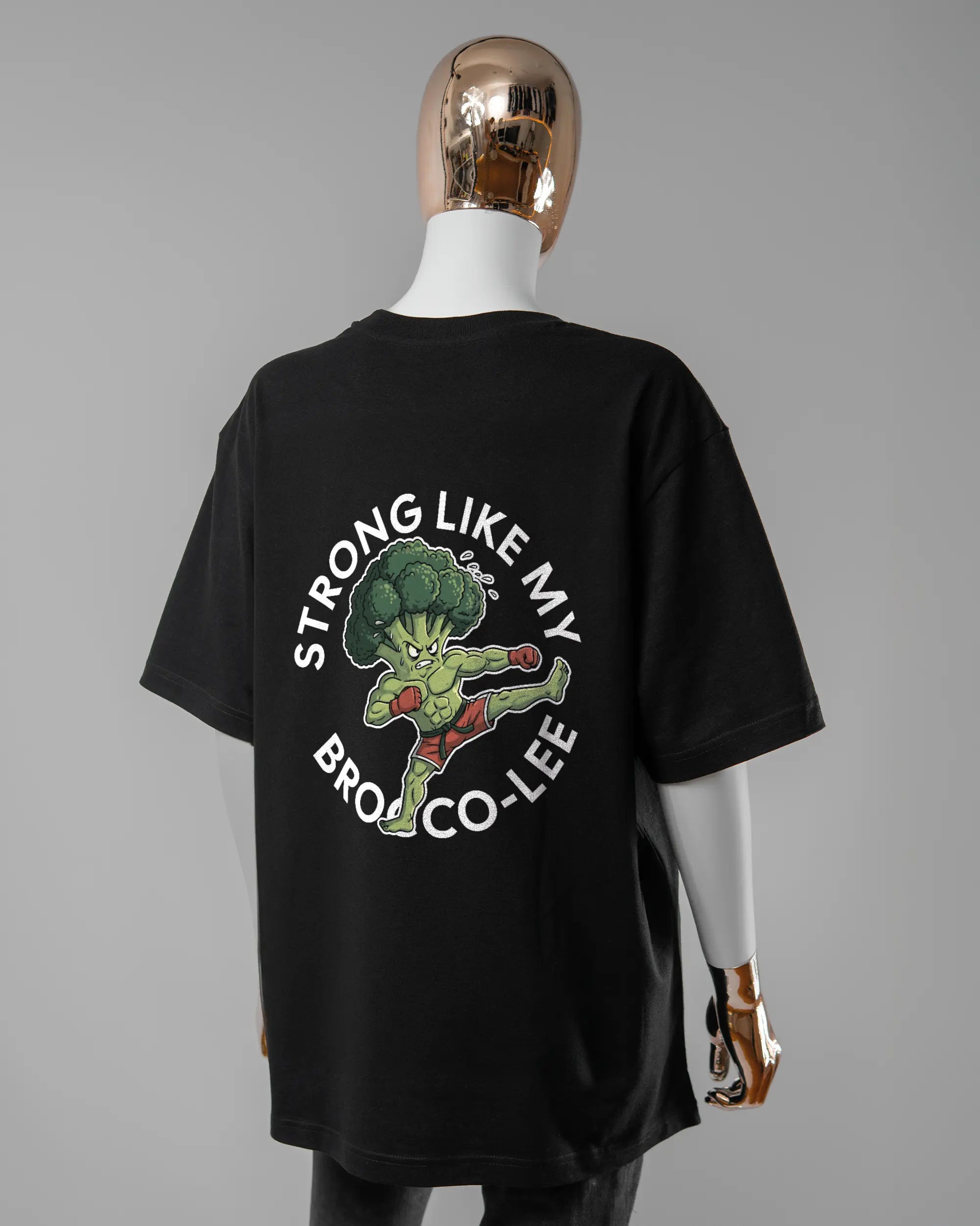 Rückseite des Basic Unisex T-Shirt Oversized von Maondo mit dem Design Brocco-Lee in der Farbe Black und in der Größe S getragen von einer femininen Puppe