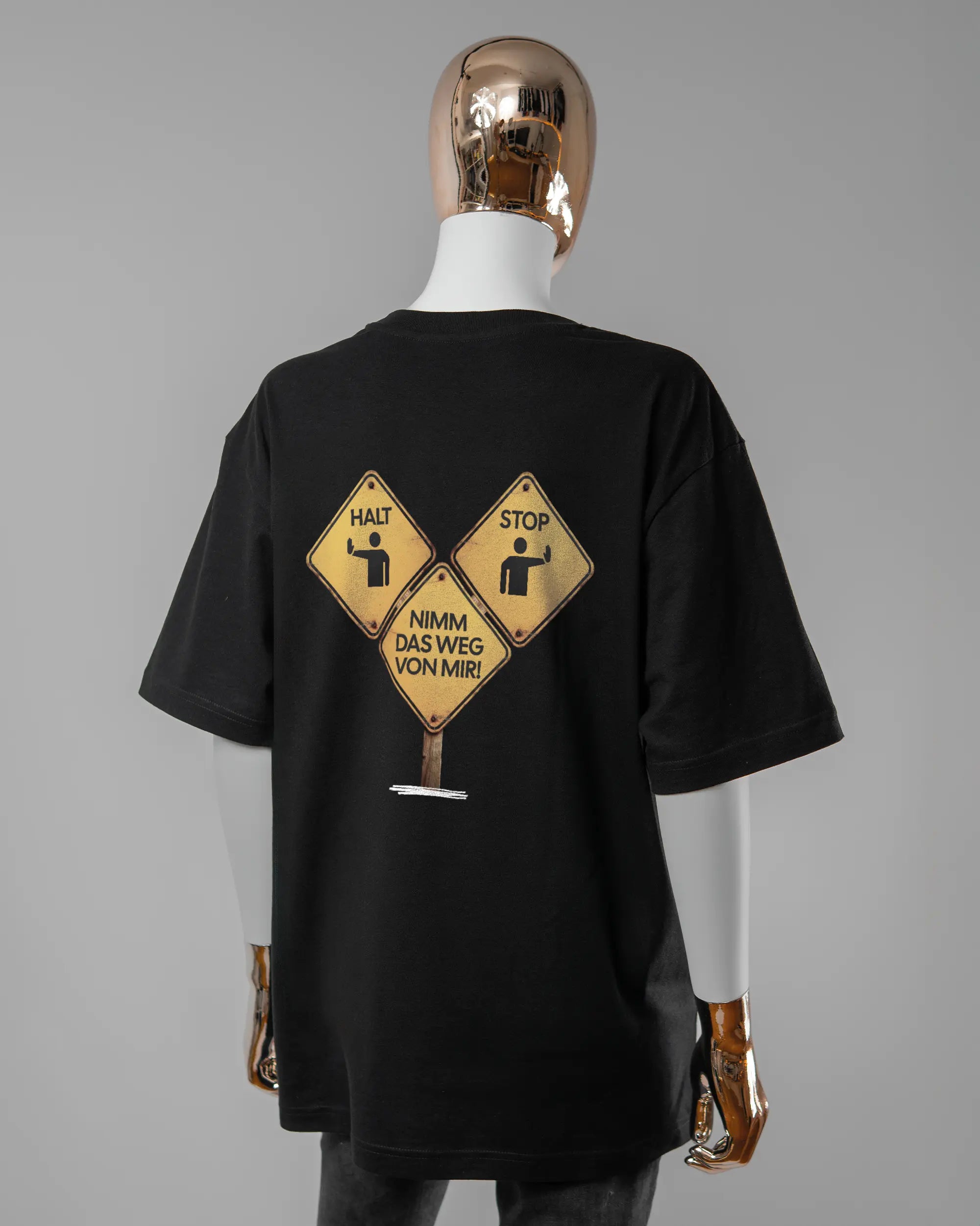 Rückseite des Basic Unisex T-Shirt Oversized von Maondo mit dem Design Schutzschild in der Farbe Black und in der Größe S getragen von einer femininen Puppe