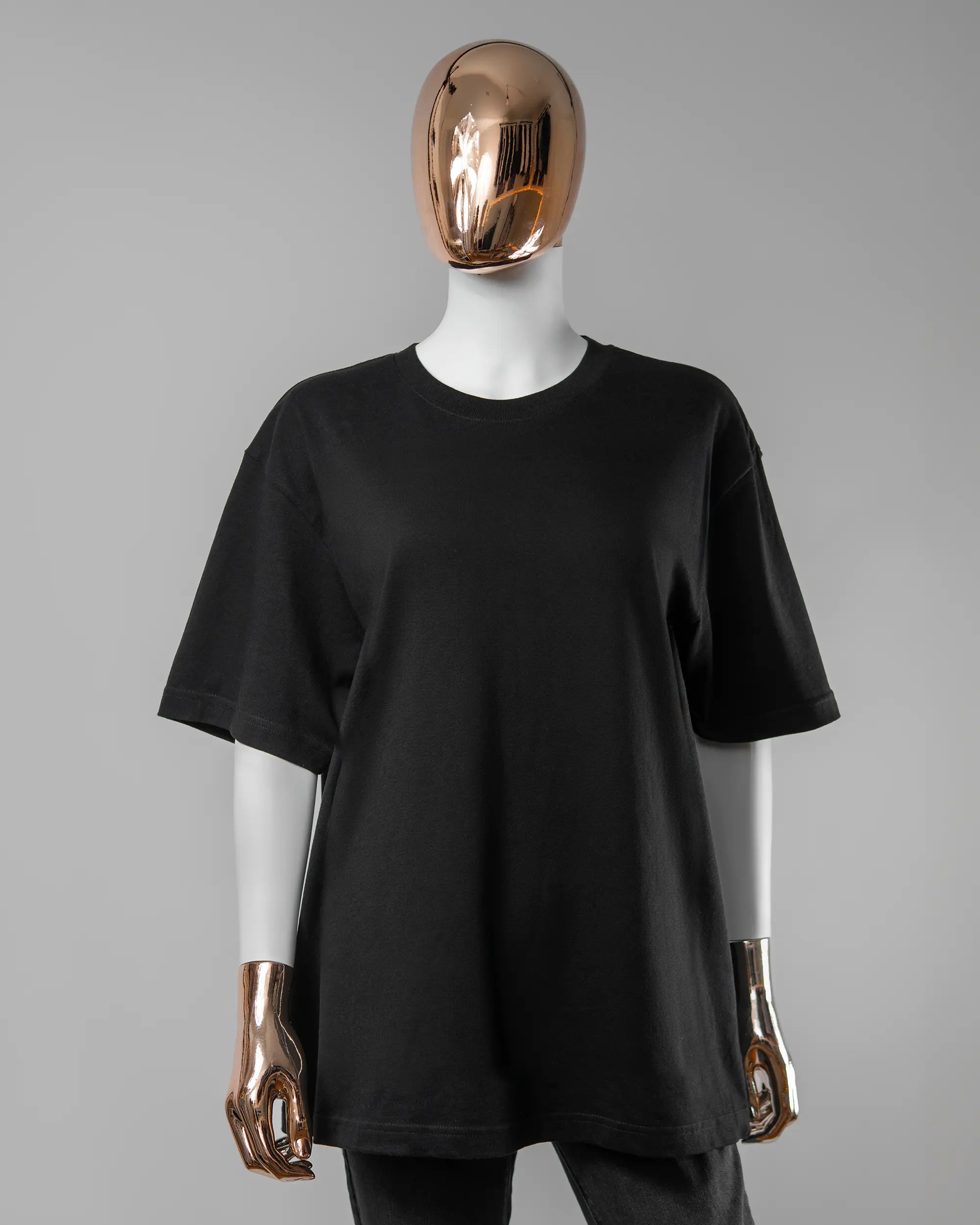 Vorderseite des Basic Unisex T-Shirt Oversized von Maondo ohne Motiv in der Farbe Black und in der Größe S getragen von einer femininen Puppe