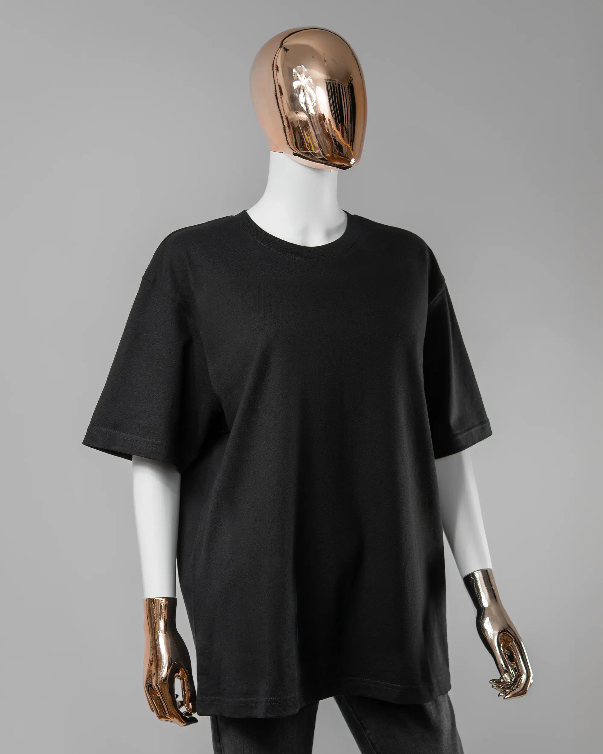 Vorderseite des Basic Unisex T-Shirt Oversized von Maondo ohne Motiv in der Farbe Black und in der Größe S getragen von einer femininen Puppe