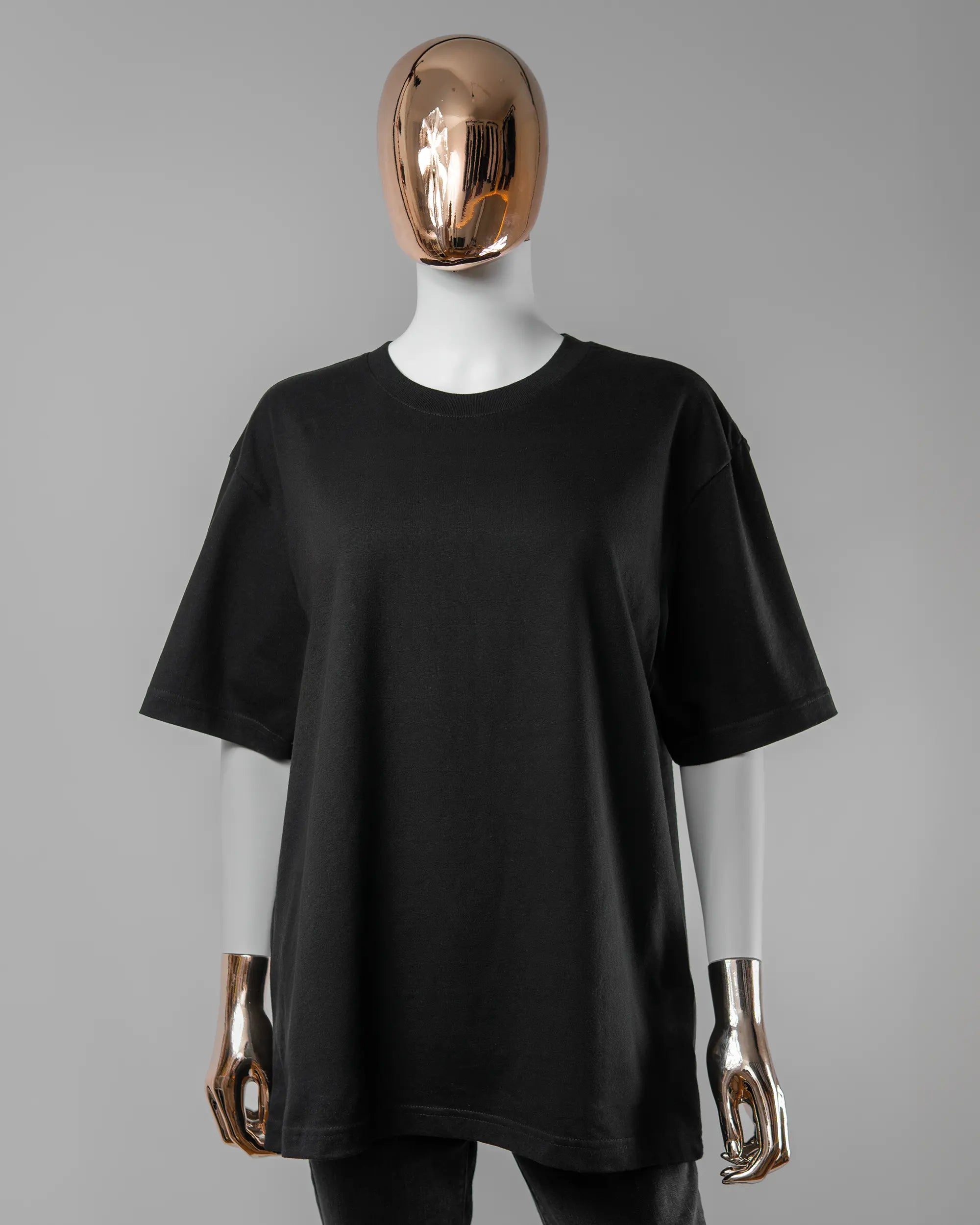 Vorderseite des Basic Unisex T-Shirt Oversized von Maondo ohne Motiv in der Farbe Black und in der Größe S getragen von einer femininen Puppe