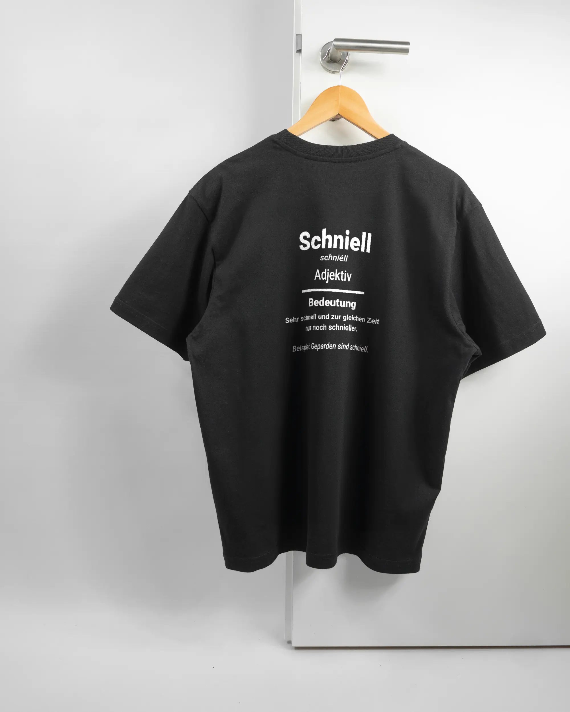 Rückseite des Basic Unisex T-Shirt Oversized von Maondo mit dem Design Schniell in der Farbe Black und in der Größe S auf einem Bügel an der Türklinke aufgehängt