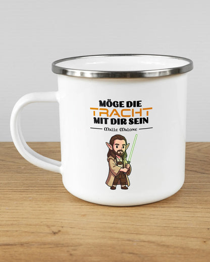 Titelbild, das die linke Seite der beidseitig bedruckten Emailletasse von Maondo mit dem Design Tracht mit dir in der Farbe White-Silver auf einem Holztisch zeigt