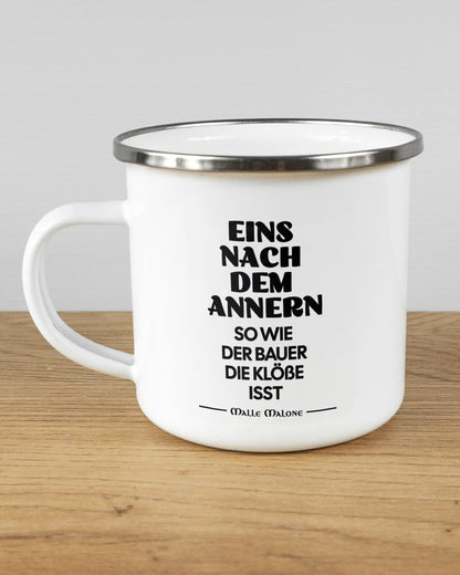 Titelbild, das die linke Seite der beidseitig bedruckten Emailletasse von Maondo mit dem Design Eins nach dem Annern in der Farbe White-Silver auf einem Holztisch zeigt