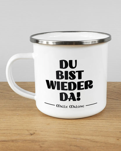 Titelbild, das die linke Seite der beidseitig bedruckten Emailletasse von Maondo mit dem Design Wieder da in der Farbe White-Silver auf einem Holztisch zeigt