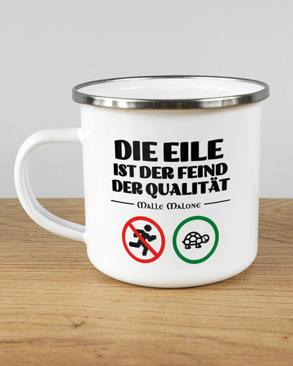 Titelbild, das die linke Seite der beidseitig bedruckten Emailletasse von Maondo mit dem Design Keine Eile in der Farbe White-Silver auf einem Holztisch zeigt