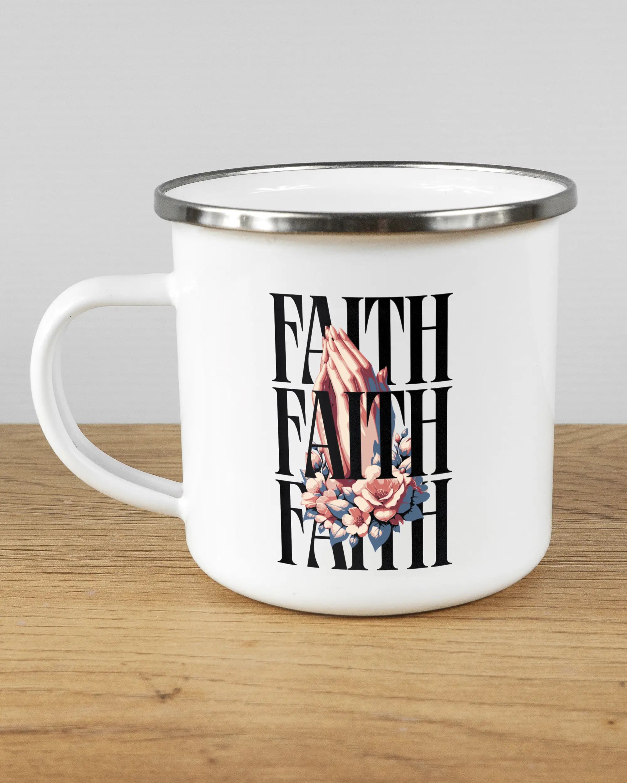 Titelbild, das die linke Seite der beidseitig bedruckten Emailletasse von Maondo mit dem Design Faith X3 in der Farbe White-Silver auf einem Holztisch zeigt