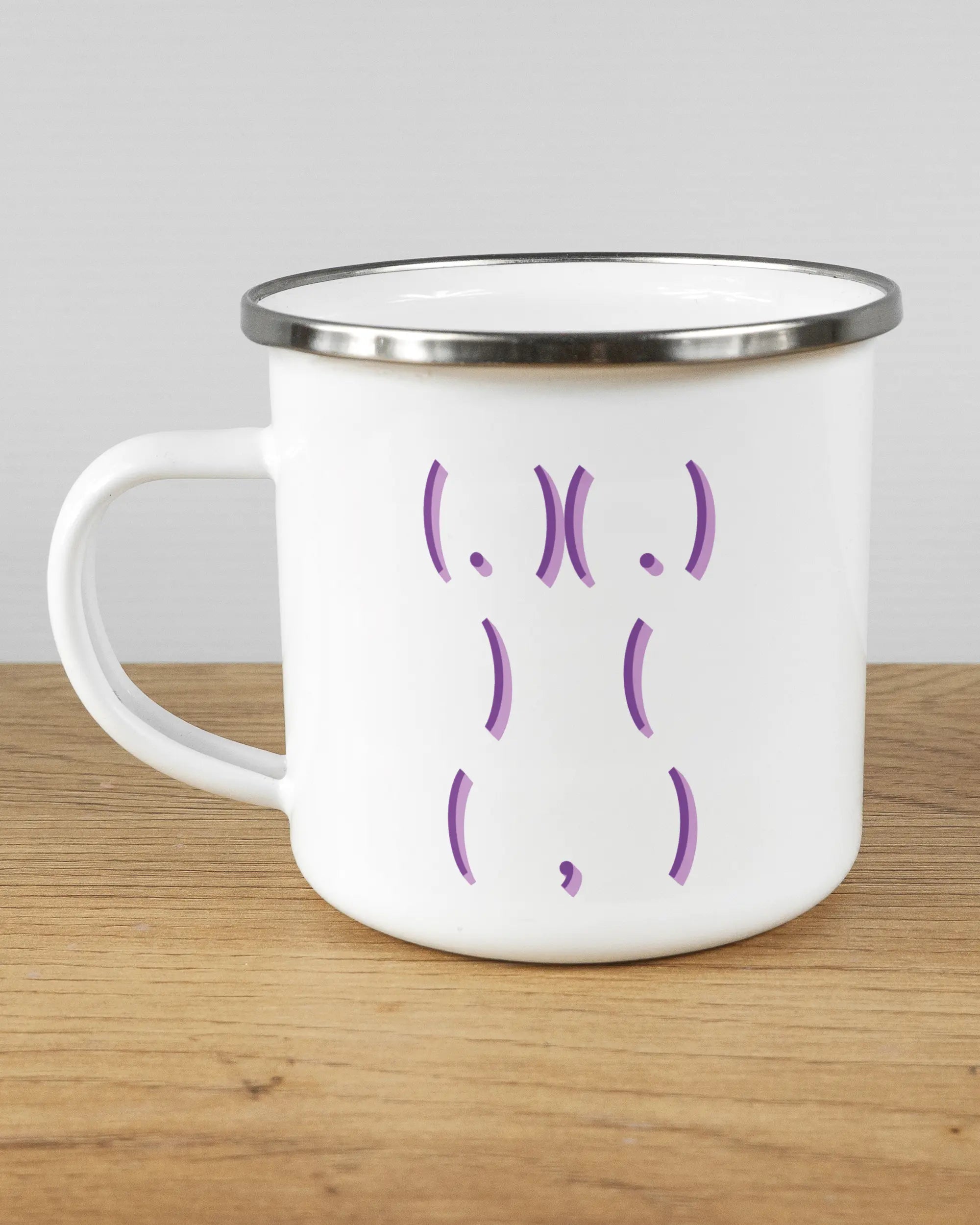 Titelbild, das die linke Seite der beidseitig bedruckten Emailletasse von Maondo mit dem Design Body Language in der Farbe White-Silver auf einem Holztisch zeigt