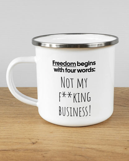 Titelbild, das die linke Seite der beidseitig bedruckten Emailletasse von Maondo mit dem Design 4 Freedom in der Farbe White-Silver auf einem Holztisch zeigt