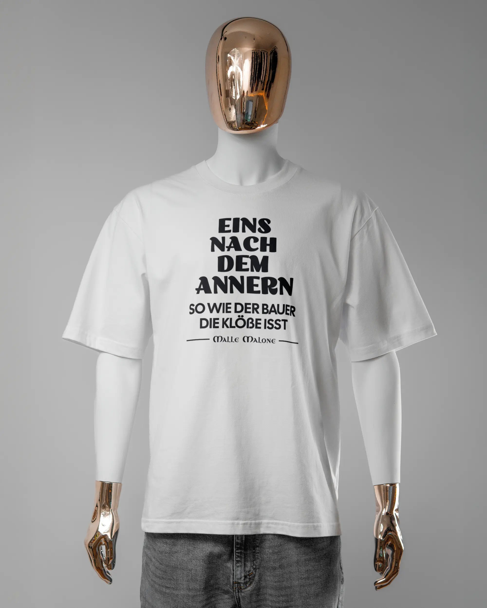 Vorderseite des Basic Unisex T-Shirt Oversized von Maondo mit dem Design Eins nach dem Annern in der Farbe White und in der Größe L getragen von einer maskulinen Puppe
