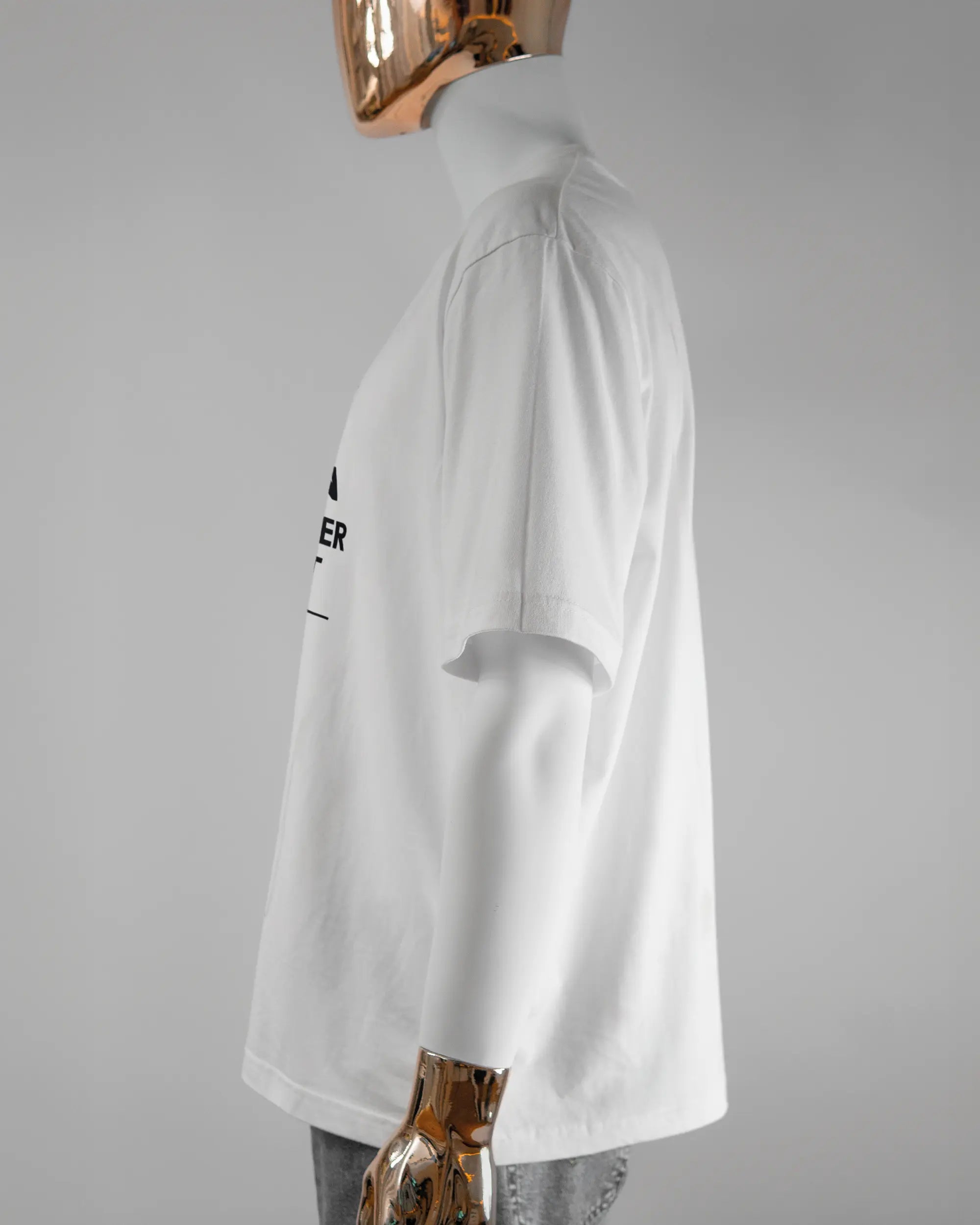 Seitenansicht des Basic Unisex T-Shirt Oversized von Maondo mit dem Design Eins nach dem Annern vorne in der Farbe White und in der Größe L getragen von einer maskulinen Puppe