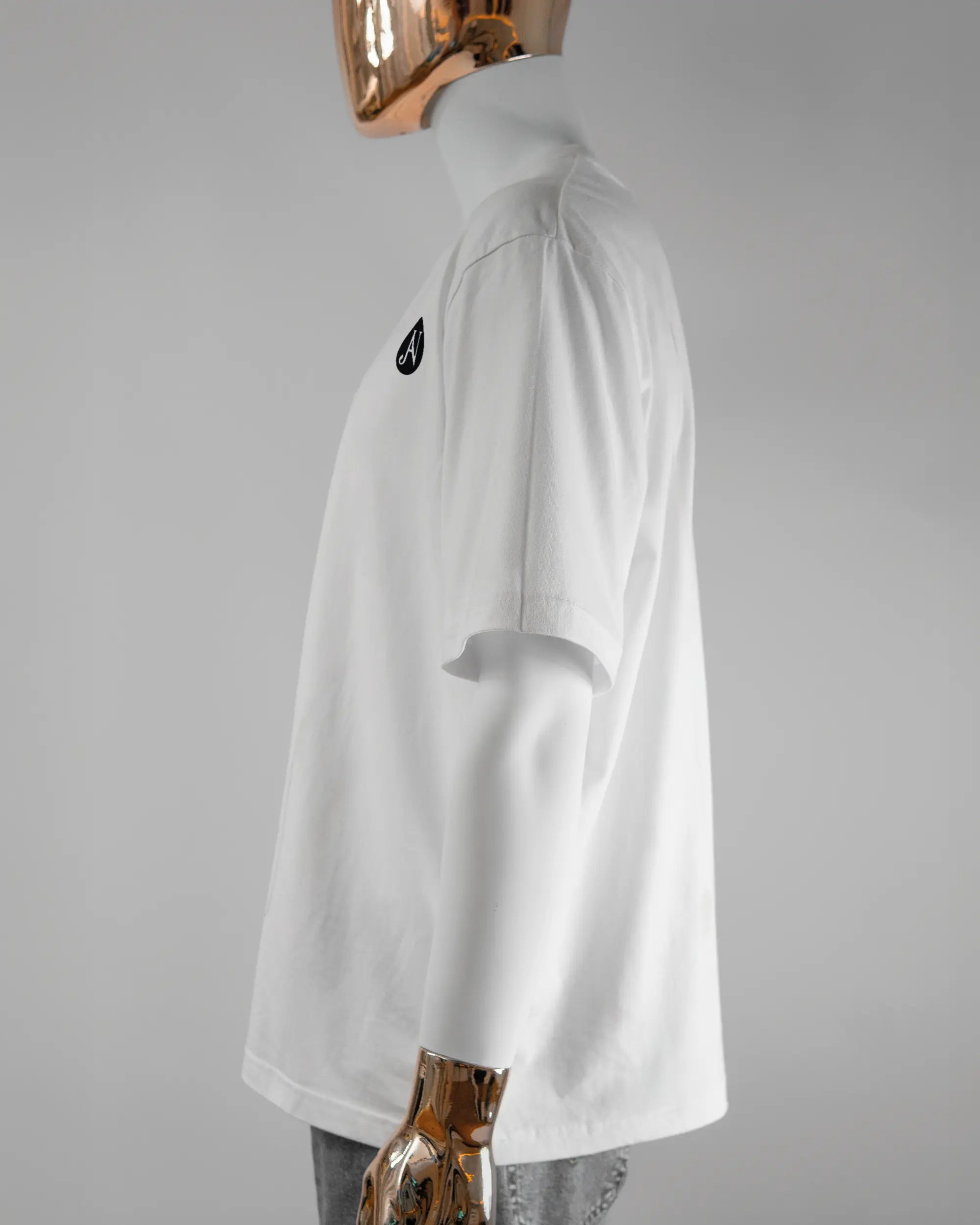 Seitenansicht des Basic Unisex T-Shirt Oversized von Maondo mit dem Design JB1 vorne in der Farbe White und in der Größe L getragen von einer maskulinen Puppe