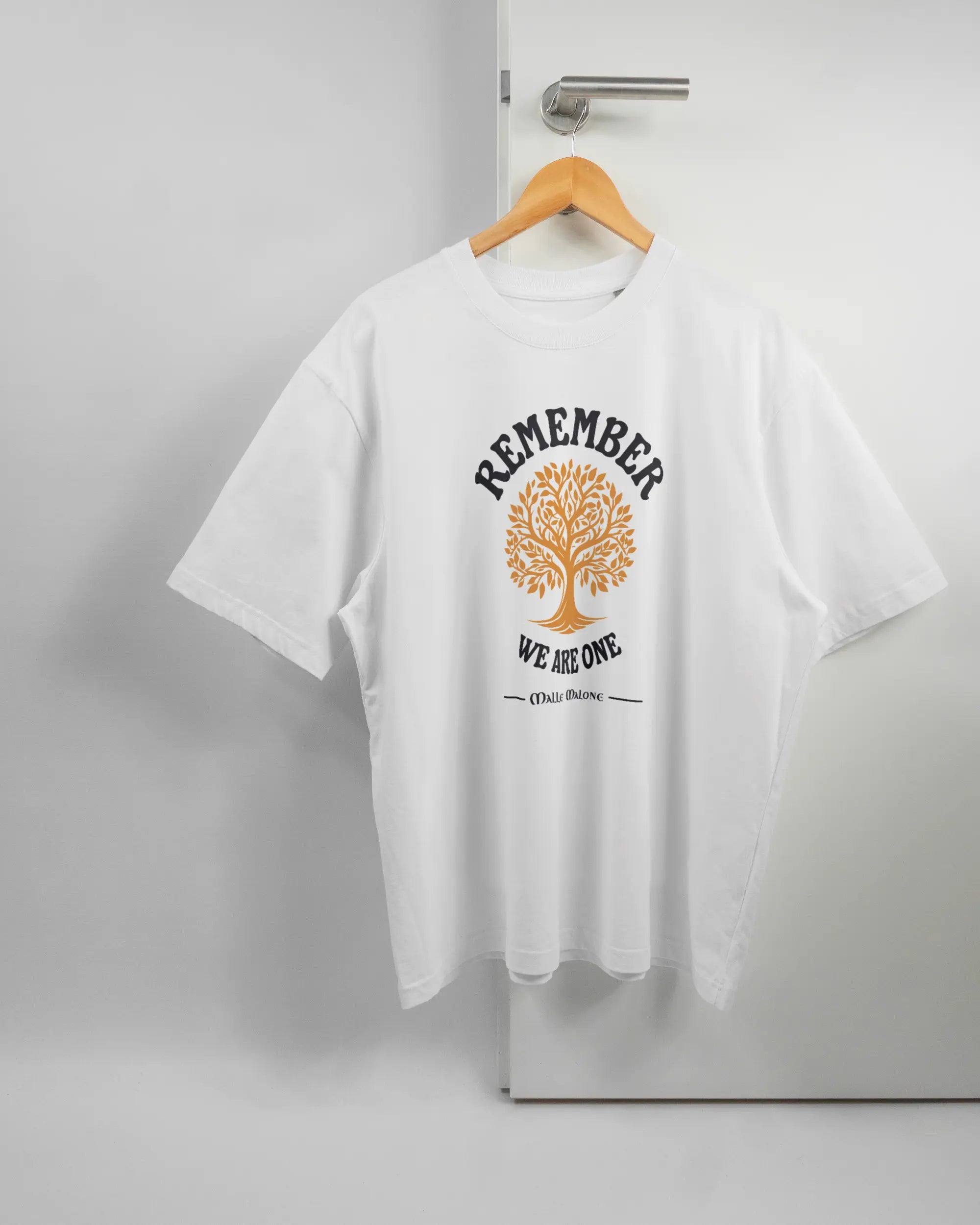 Vorderseite des Basic Unisex T-Shirt Oversized von Maondo mit dem Design We are one in der Farbe White und in der Größe L auf einem Bügel an der Türklinke aufgehängt