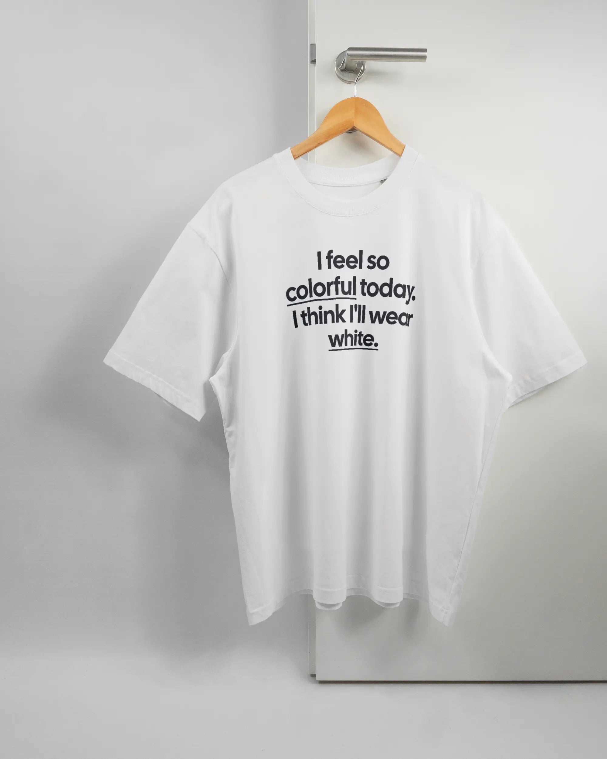 Vorderseite des Basic Unisex T-Shirt Oversized von Maondo mit dem Design Colorful Day in der Farbe White und in der Größe L auf einem Bügel an der Türklinke aufgehängt