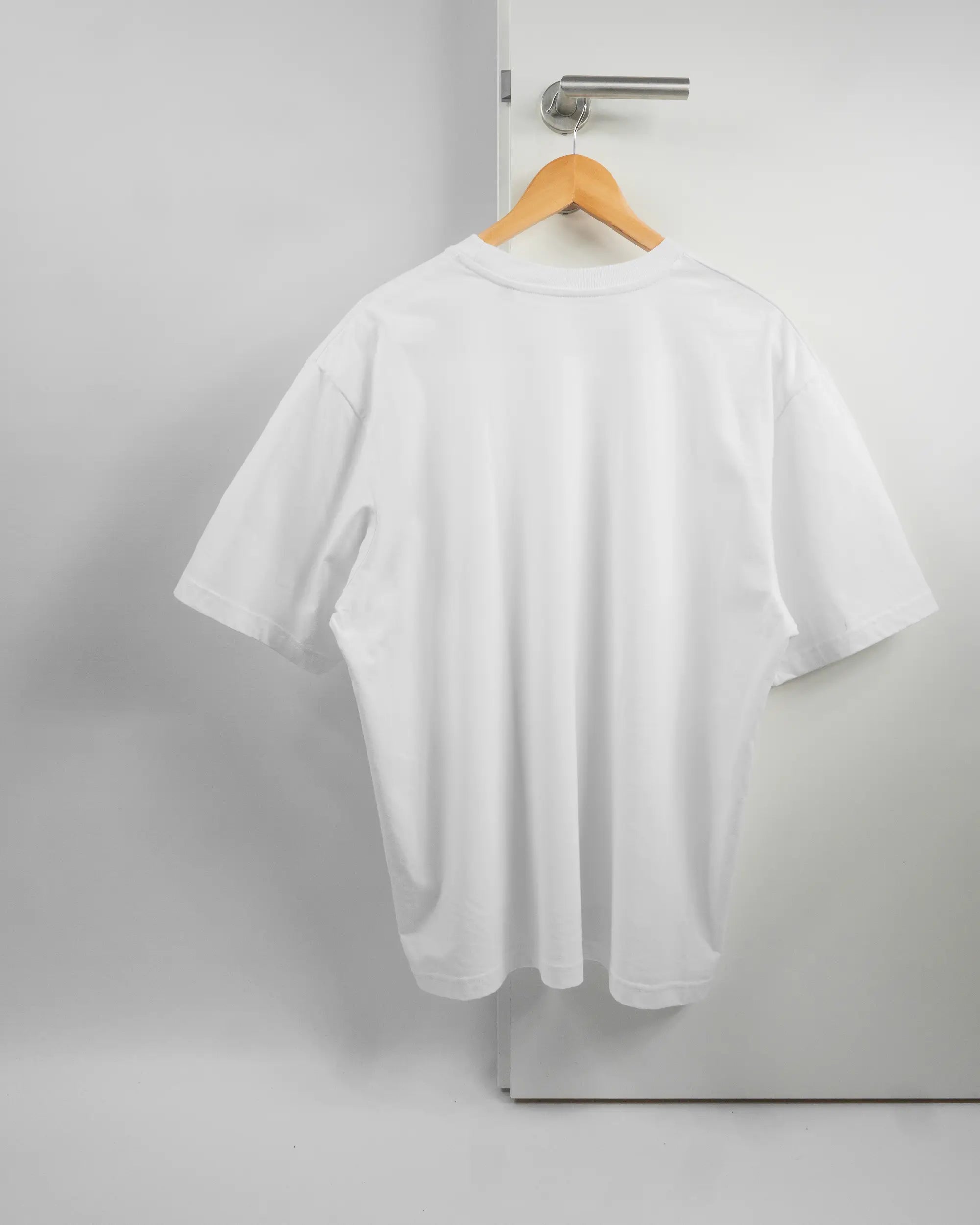 Rückseite des Basic Unisex T-Shirt Oversized von Maondo ohne Motiv in der Farbe White und in der Größe L auf einem Bügel an der Türklinke aufgehängt
