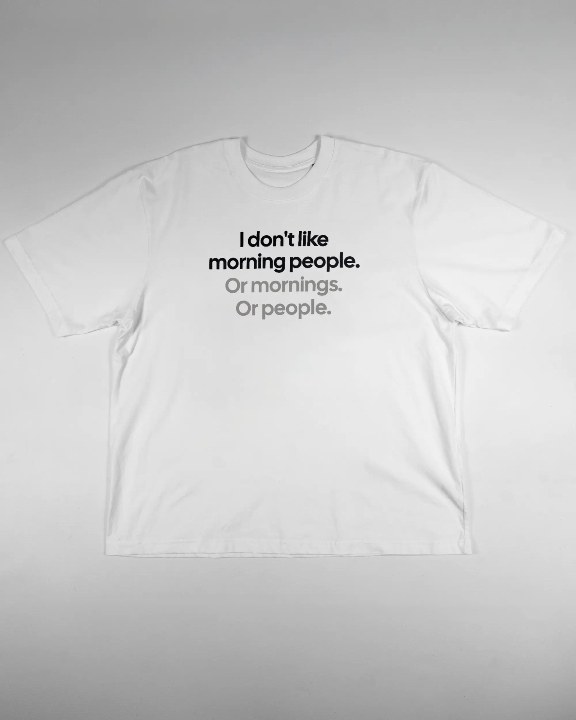 Vorderseite des Basic Unisex T-Shirt Oversized von Maondo mit dem Design Morning Person in der Farbe White und in der Größe L flach auf den Boden gelegt