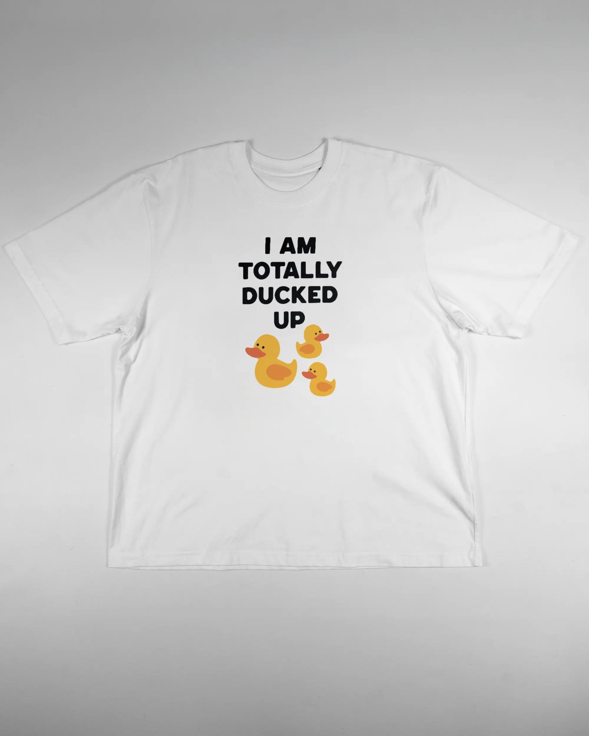 Vorderseite des Basic Unisex T-Shirt Oversized von Maondo mit dem Design Ducked Up in der Farbe White und in der Größe L flach auf den Boden gelegt