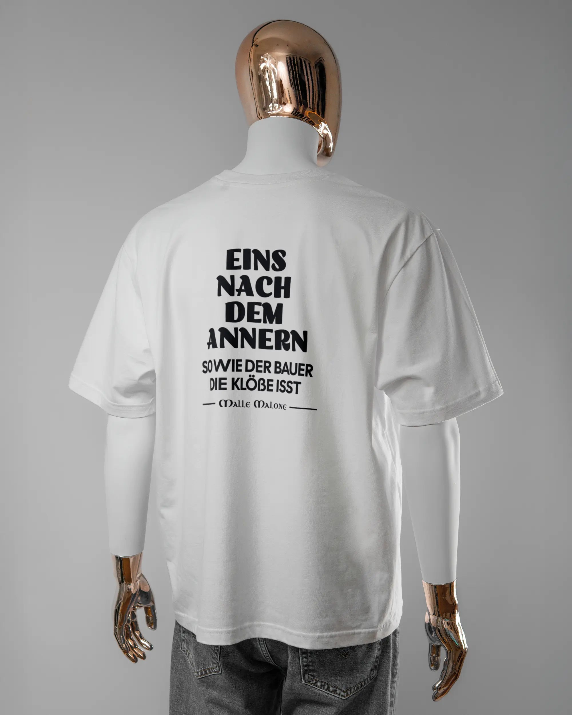 Rückseite des Basic Unisex T-Shirt Oversized von Maondo mit dem Design Eins nach dem Annern in der Farbe White und in der Größe L getragen von einer maskulinen Puppe