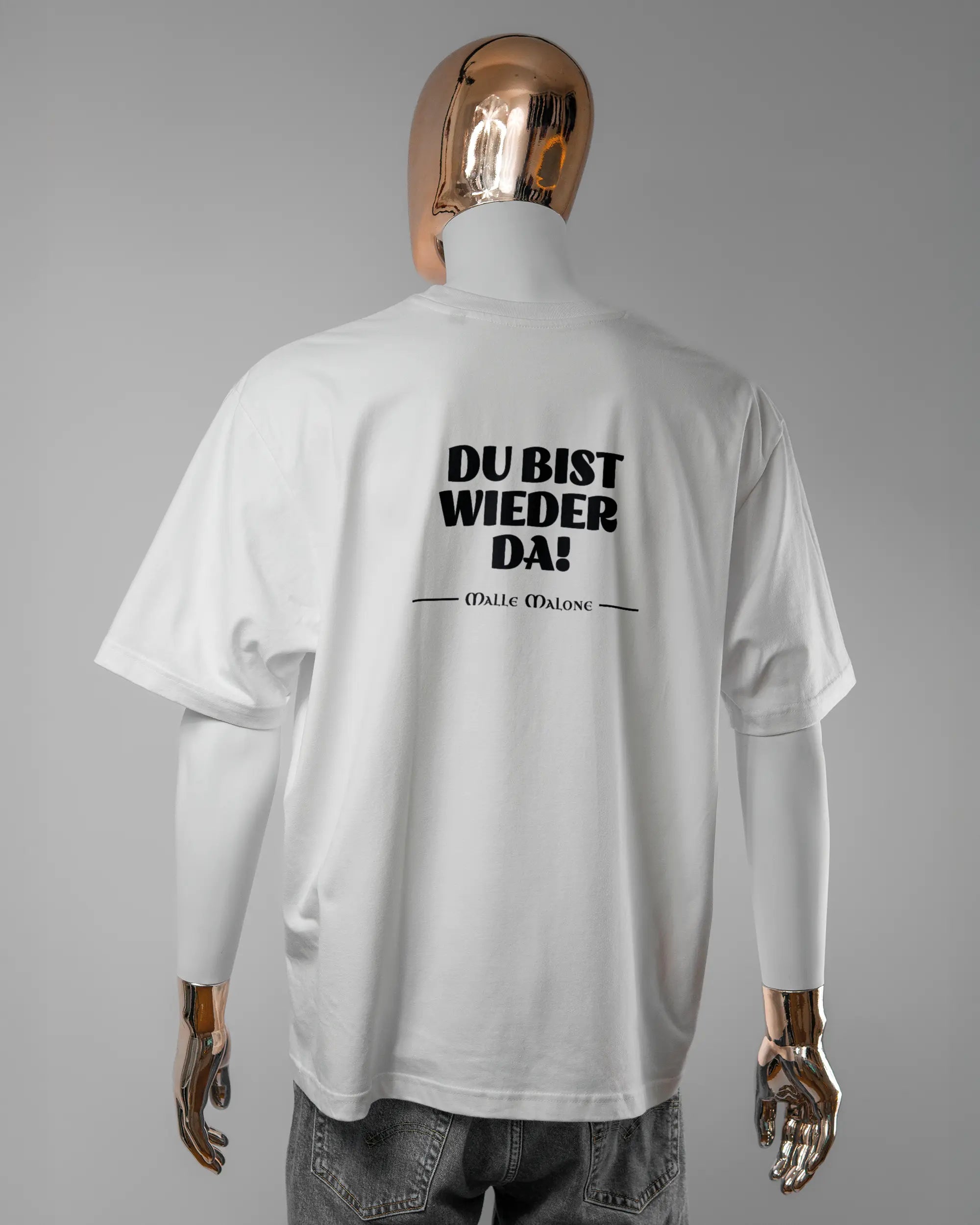 Rückseite des Basic Unisex T-Shirt Oversized von Maondo mit dem Design Wieder da in der Farbe White und in der Größe L getragen von einer maskulinen Puppe