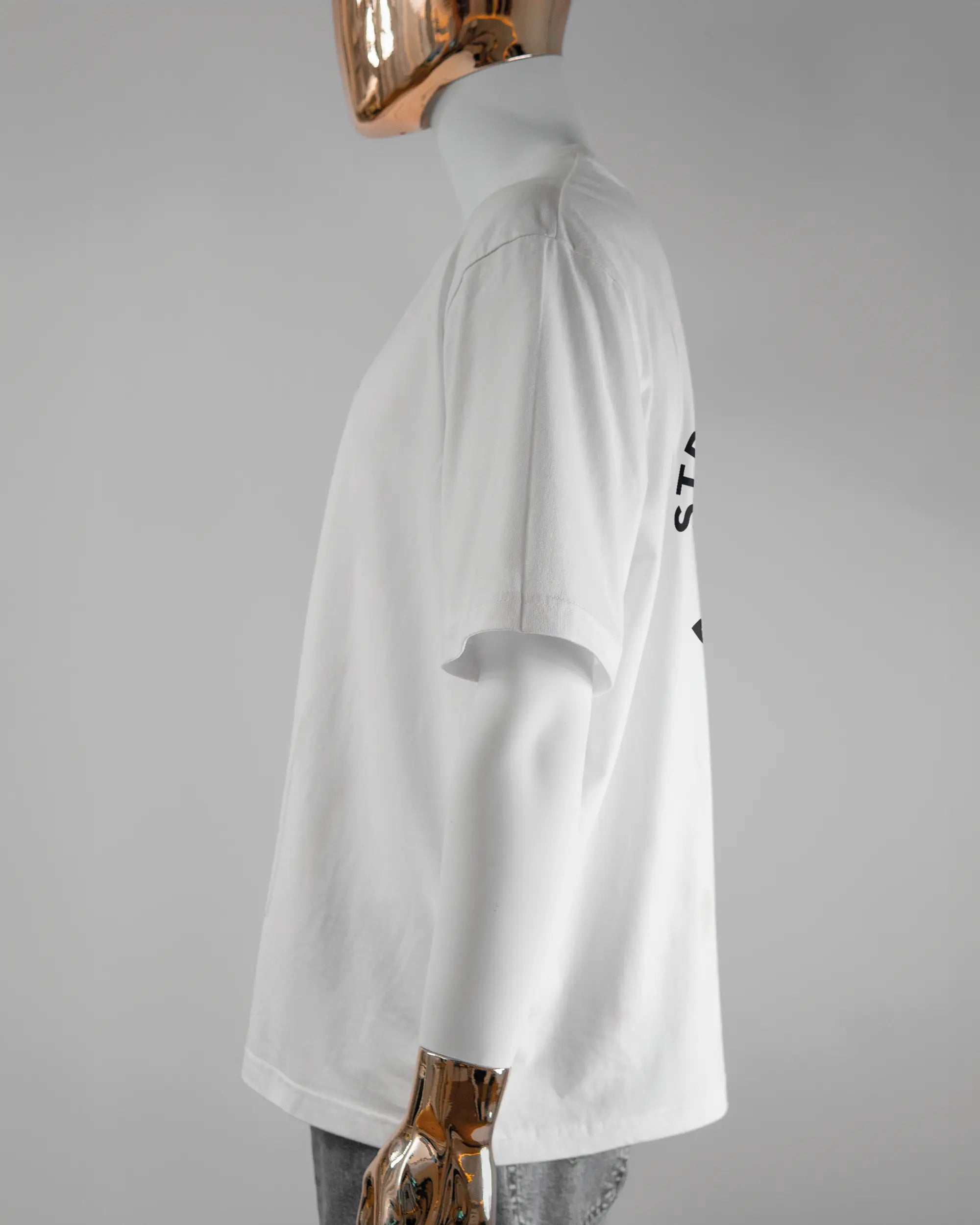 Seitenansicht des Basic Unisex T-Shirt Oversized von Maondo mit dem Design Brocco-Lee hinten in der Farbe White und in der Größe L getragen von einer maskulinen Puppe