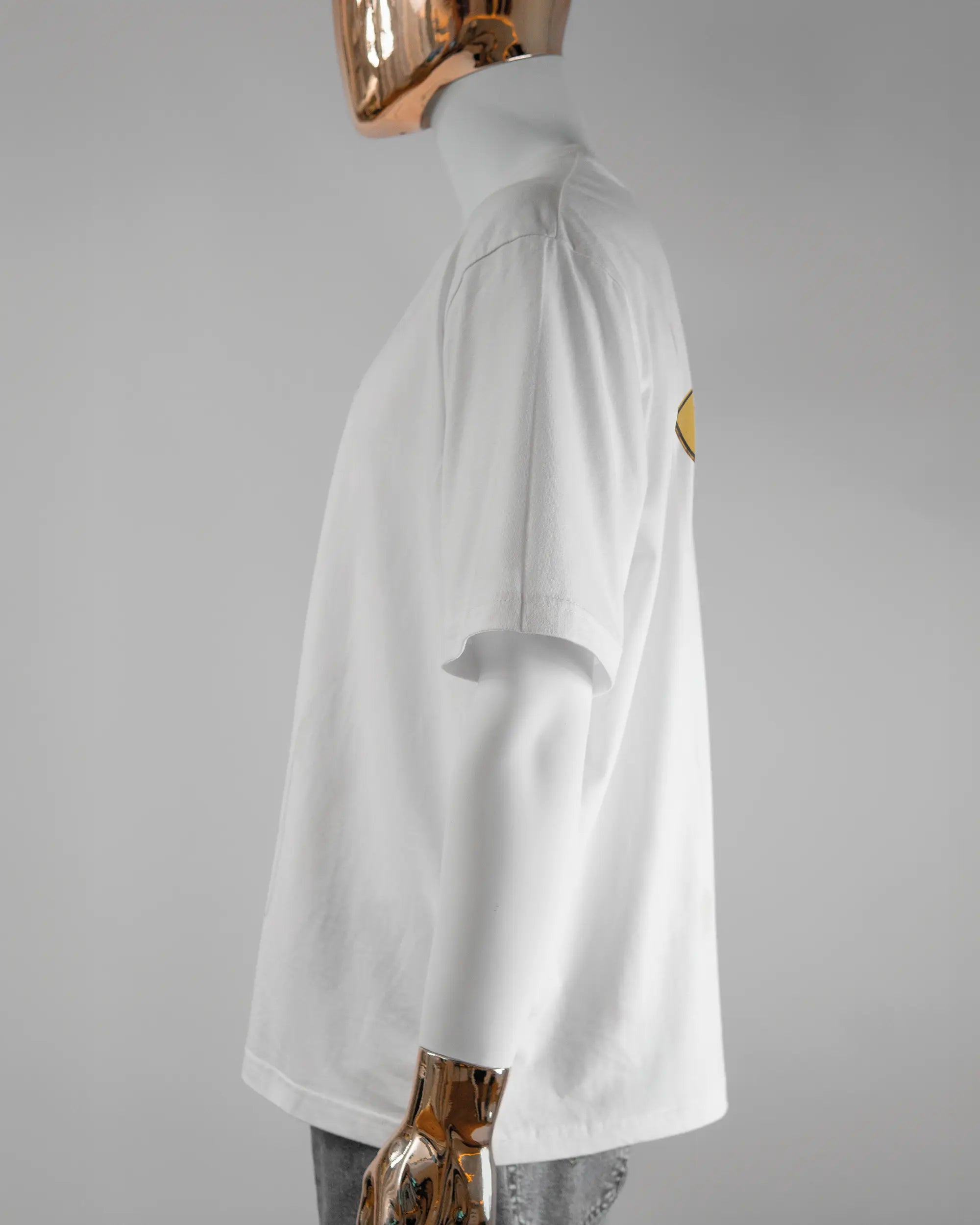 Seitenansicht des Basic Unisex T-Shirt Oversized von Maondo mit dem Design Schutzschild hinten in der Farbe White und in der Größe L getragen von einer maskulinen Puppe