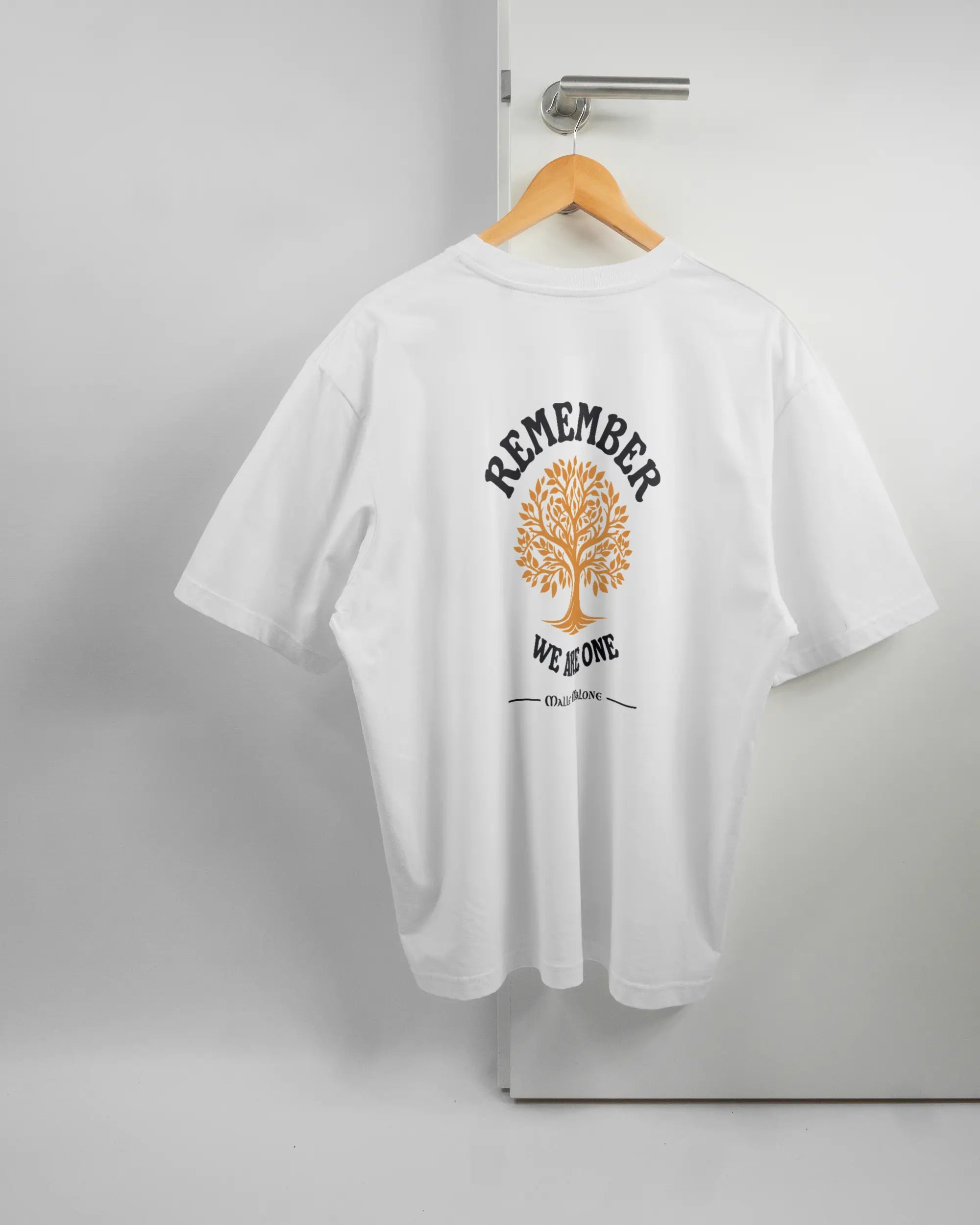 Rückseite des Basic Unisex T-Shirt Oversized von Maondo mit dem Design We are one in der Farbe White und in der Größe L auf einem Bügel an der Türklinke aufgehängt