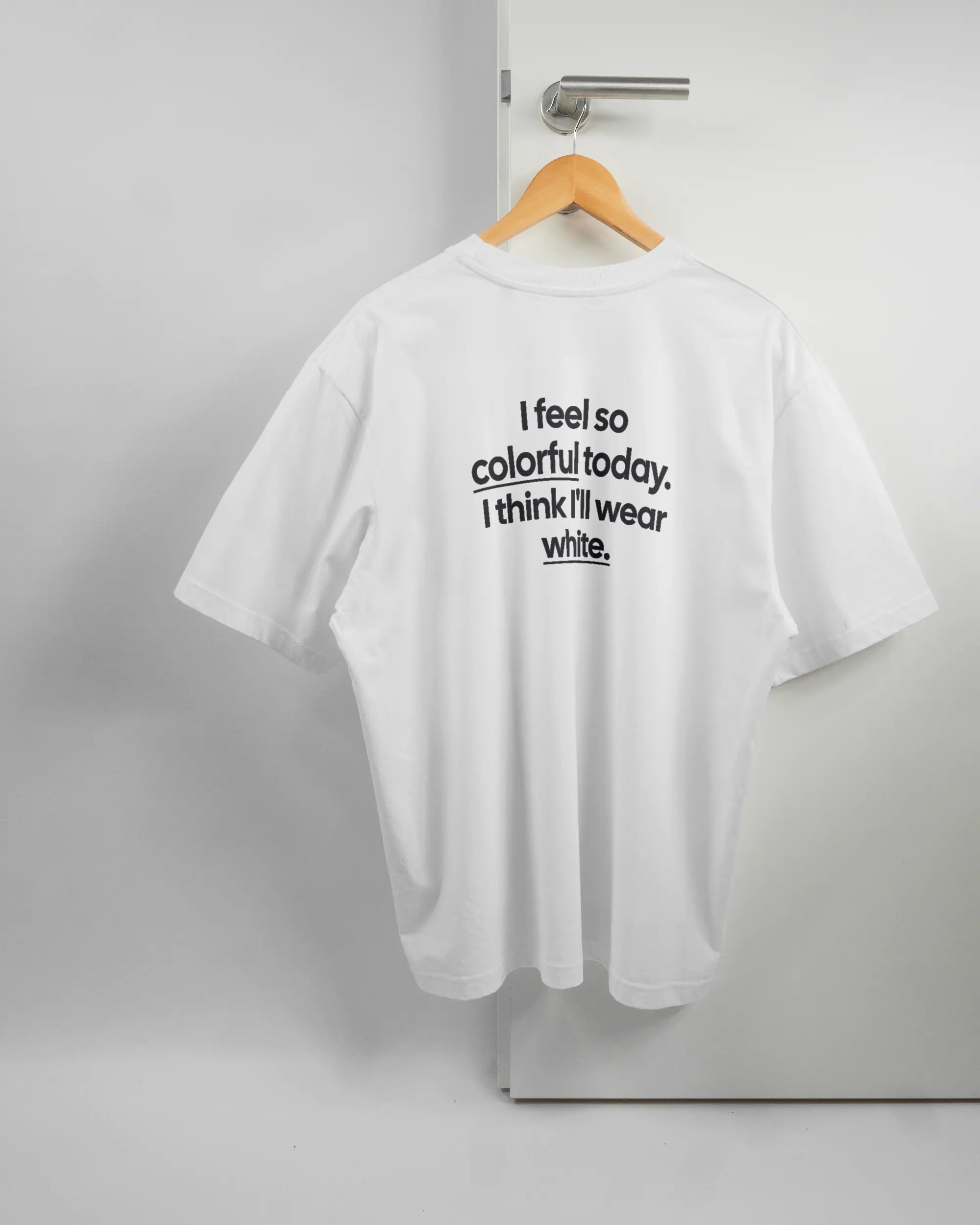 Rückseite des Basic Unisex T-Shirt Oversized von Maondo mit dem Design Colorful Day in der Farbe White und in der Größe L auf einem Bügel an der Türklinke aufgehängt