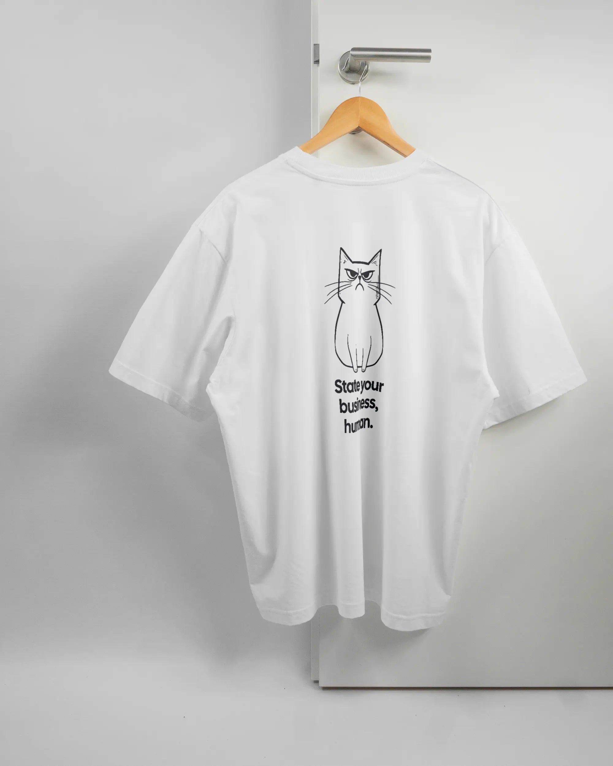Rückseite des Basic Unisex T-Shirt Oversized von Maondo mit dem Design Grumpy Purr in der Farbe White und in der Größe L auf einem Bügel an der Türklinke aufgehängt