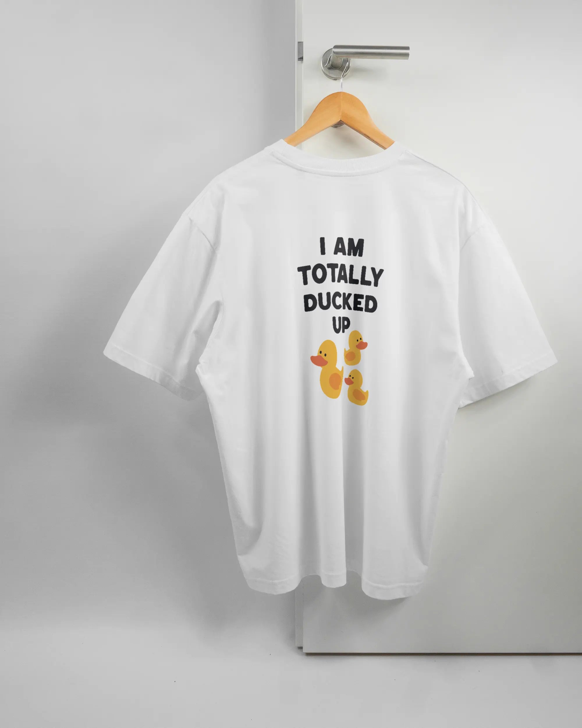 Rückseite des Basic Unisex T-Shirt Oversized von Maondo mit dem Design Ducked Up in der Farbe White und in der Größe L auf einem Bügel an der Türklinke aufgehängt