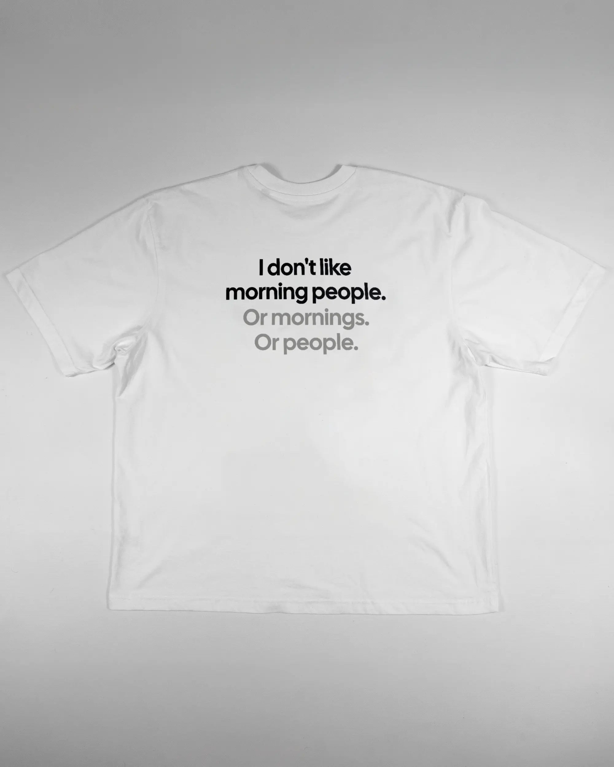 Rückseite des Basic Unisex T-Shirt Oversized von Maondo mit dem Design Morning Person in der Farbe White und in der Größe L flach auf den Boden gelegt