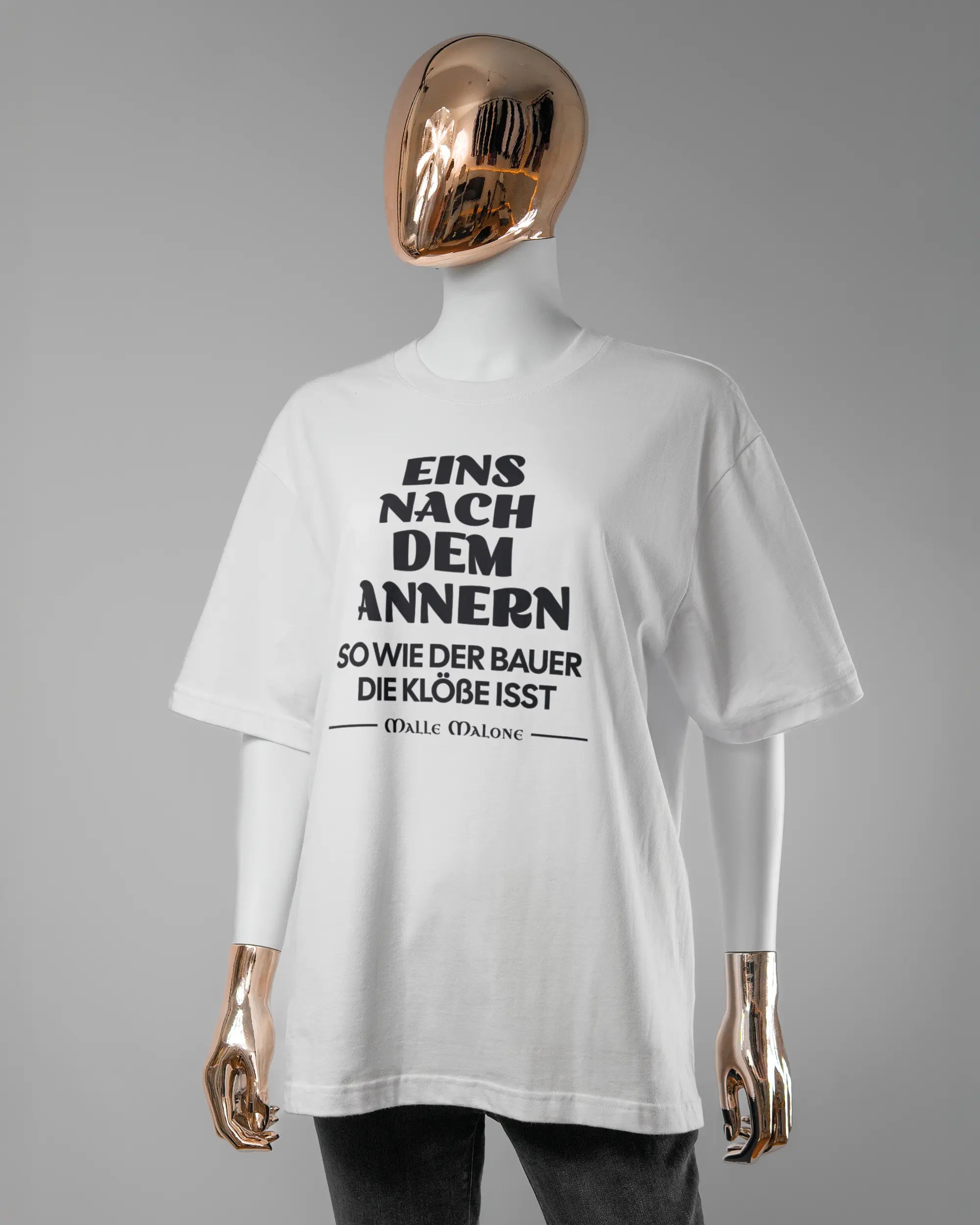 Vorderseite des Basic Unisex T-Shirt Oversized von Maondo mit dem Design Eins nach dem Annern in der Farbe White und in der Größe S getragen von einer femininen Puppe