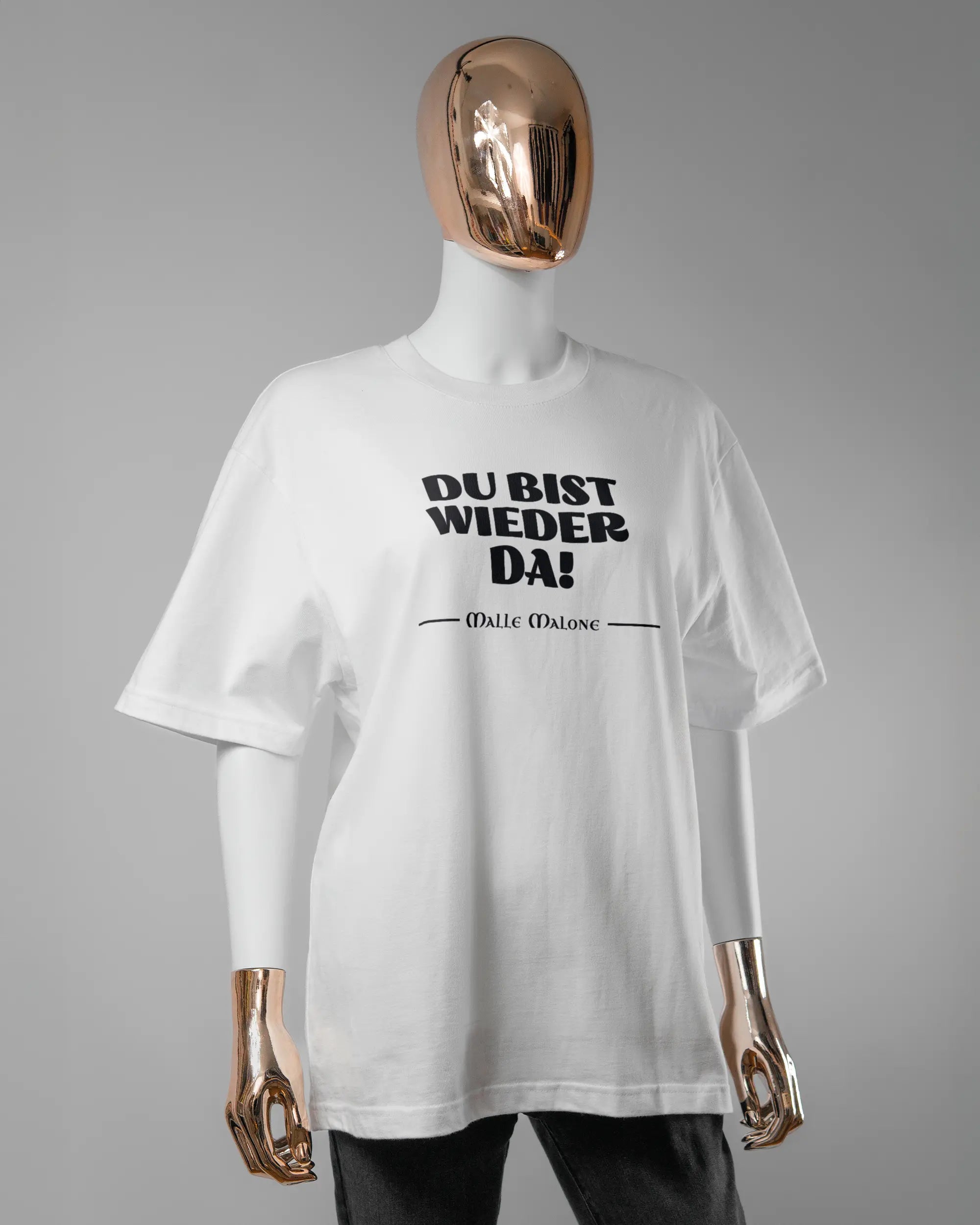 Vorderseite des Basic Unisex T-Shirt Oversized von Maondo mit dem Design Wieder da in der Farbe White und in der Größe S getragen von einer femininen Puppe