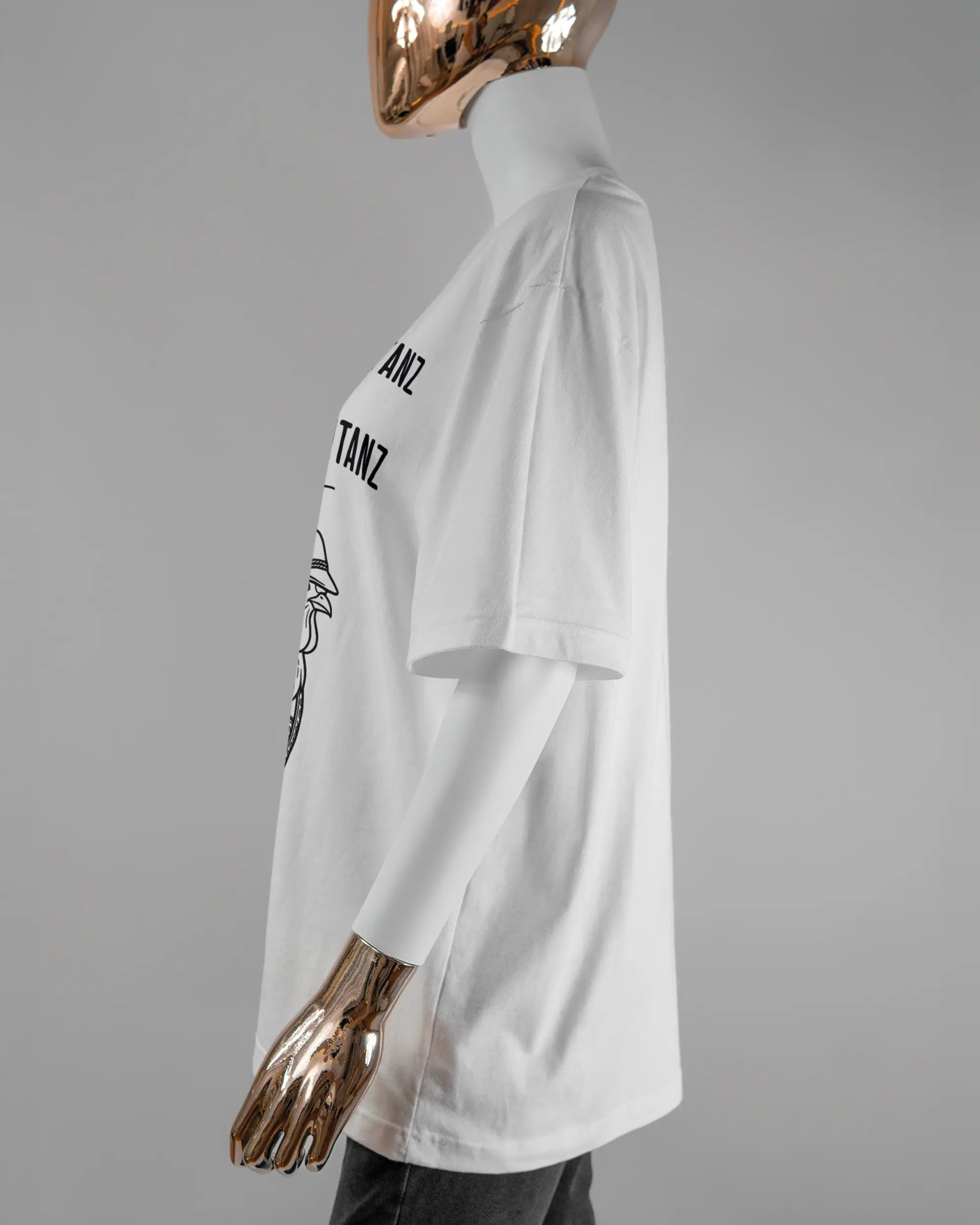Seitenansicht des Basic Unisex T-Shirt Oversized von Maondo mit dem Design Trachtentanz vorne in der Farbe White und in der Größe S getragen von einer femininen Puppe