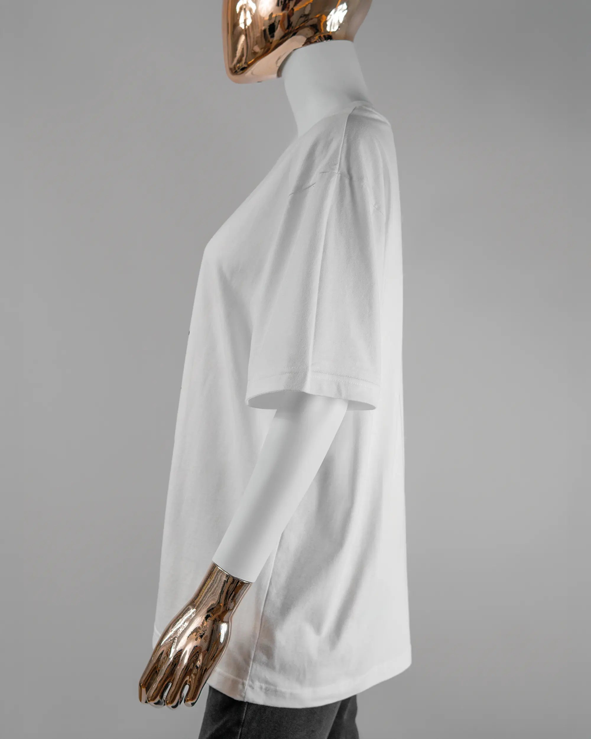 Seitenansicht des Basic Unisex T-Shirt Oversized von Maondo mit dem Design Eins nach dem Annern vorne in der Farbe White und in der Größe S getragen von einer femininen Puppe