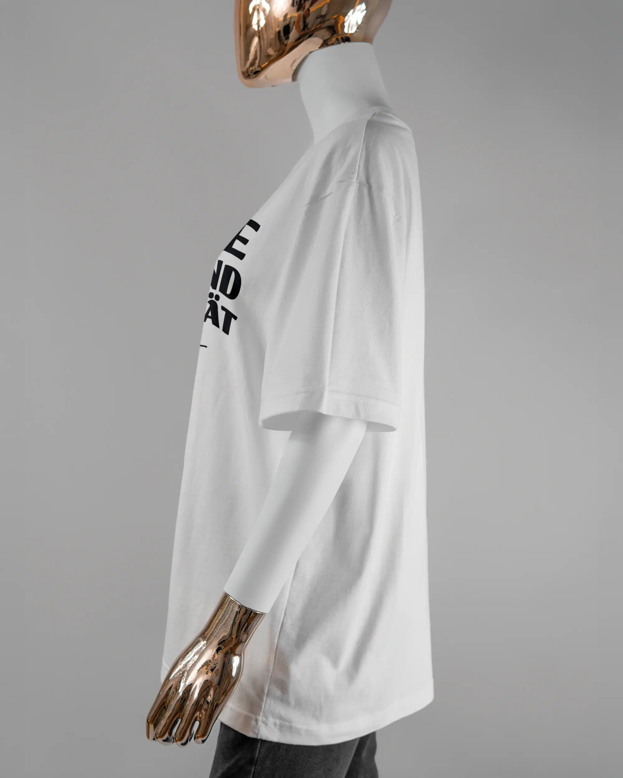 Seitenansicht des Basic Unisex T-Shirt Oversized von Maondo mit dem Design Keine Eile vorne in der Farbe White und in der Größe S getragen von einer femininen Puppe
